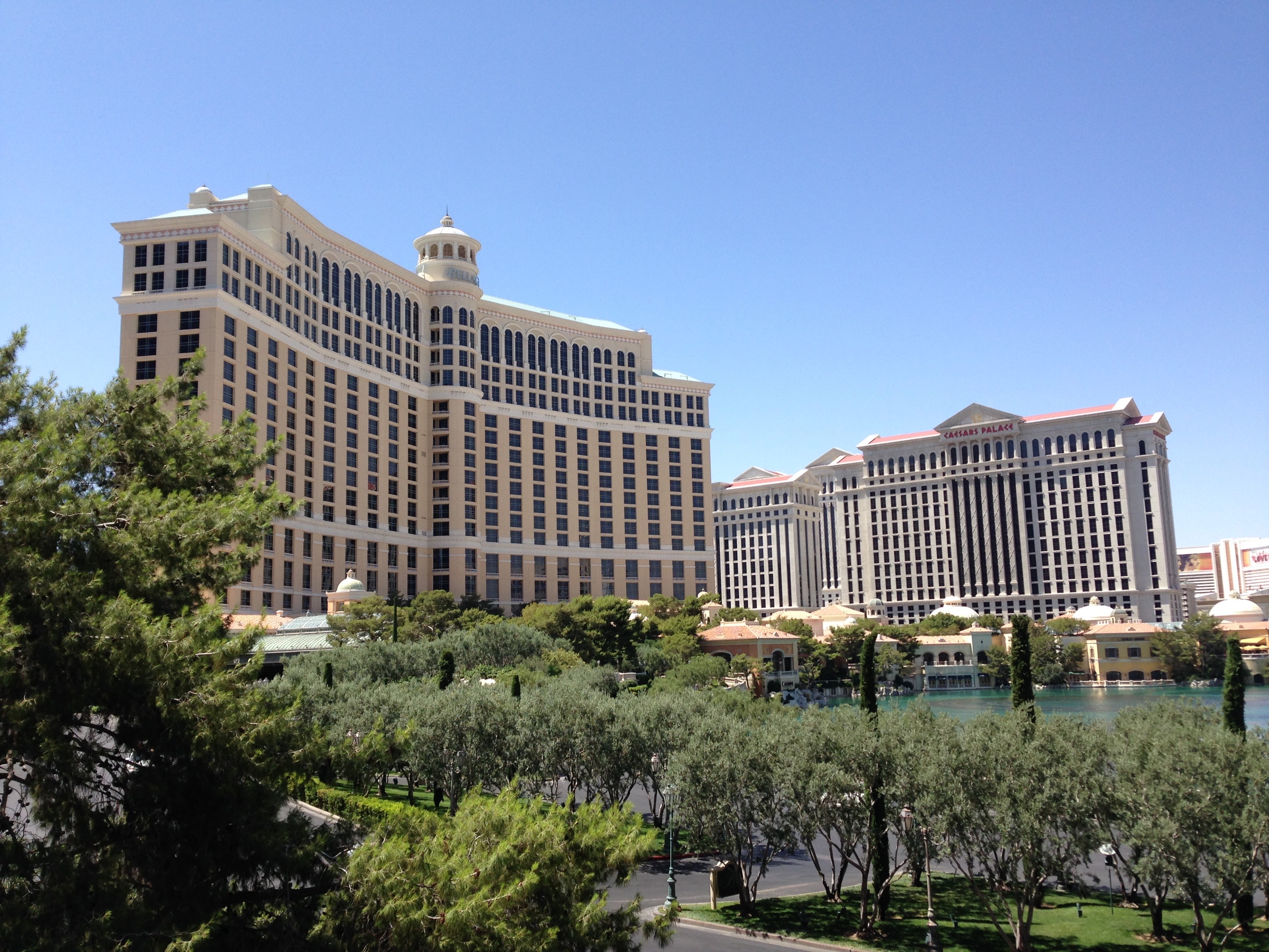 two tall buildings with a fountain and trees in between them