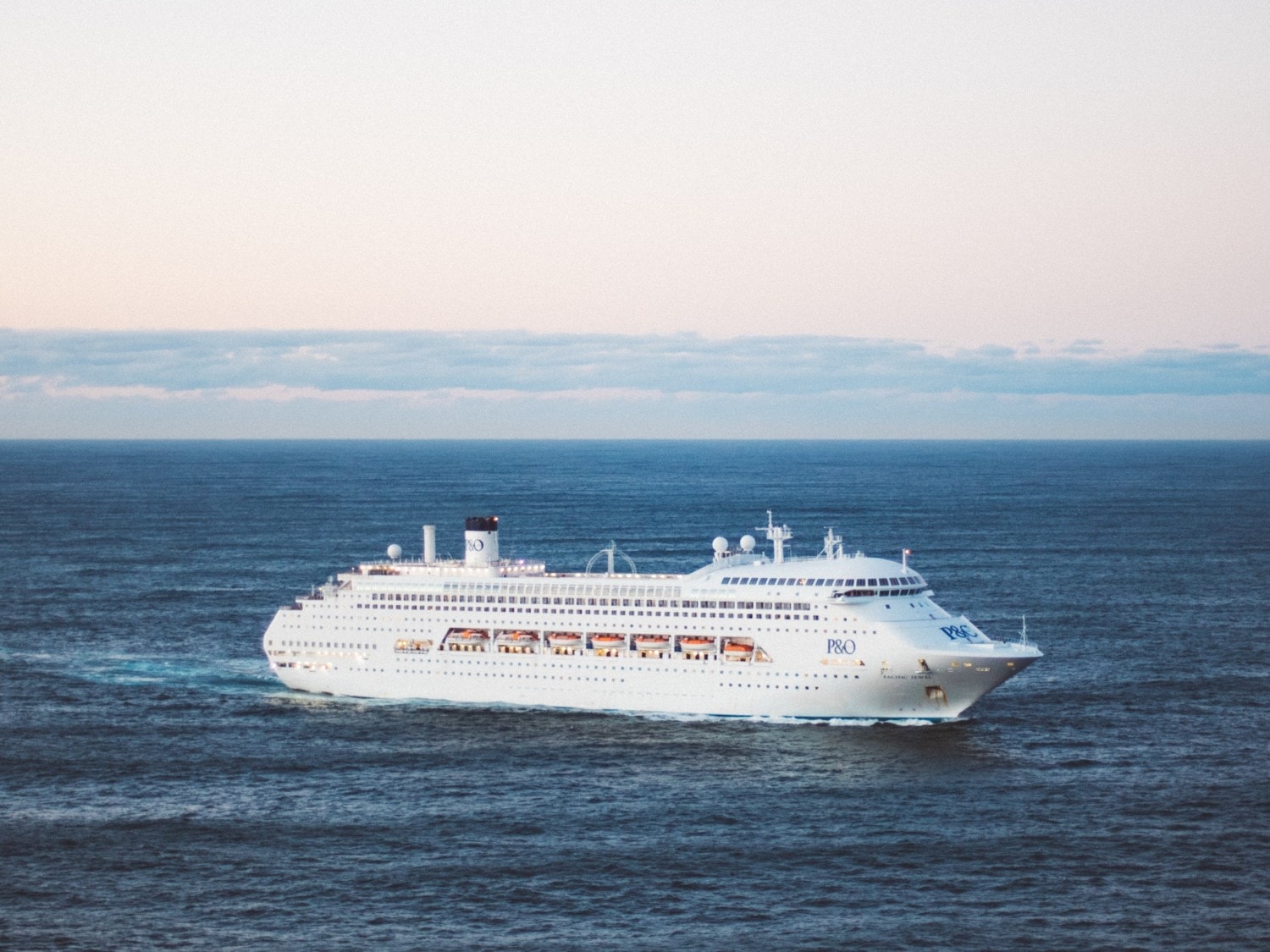 Cruise ship in middle of the ocean during sunrise.