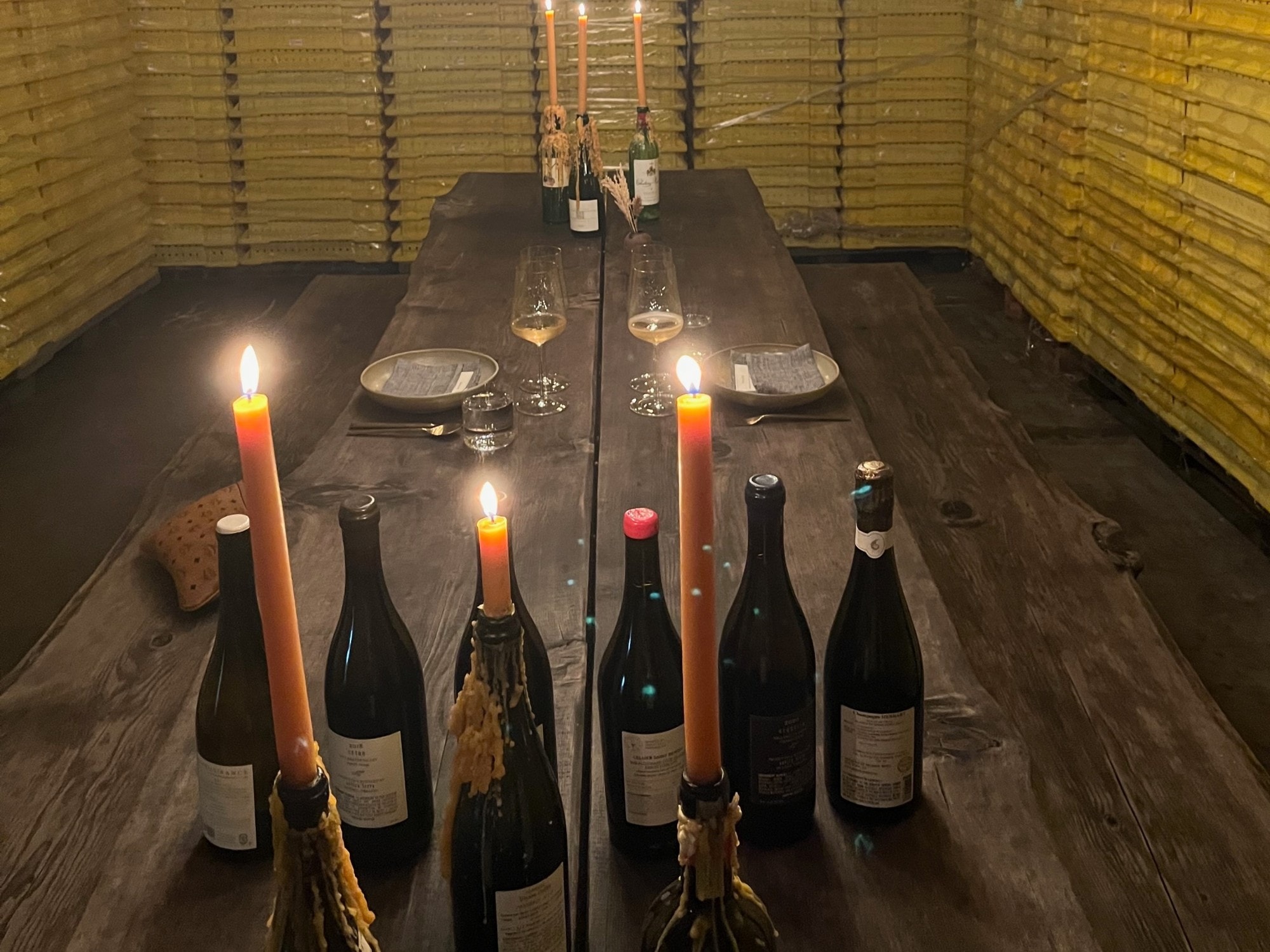 A long table with wine bottles and candles.