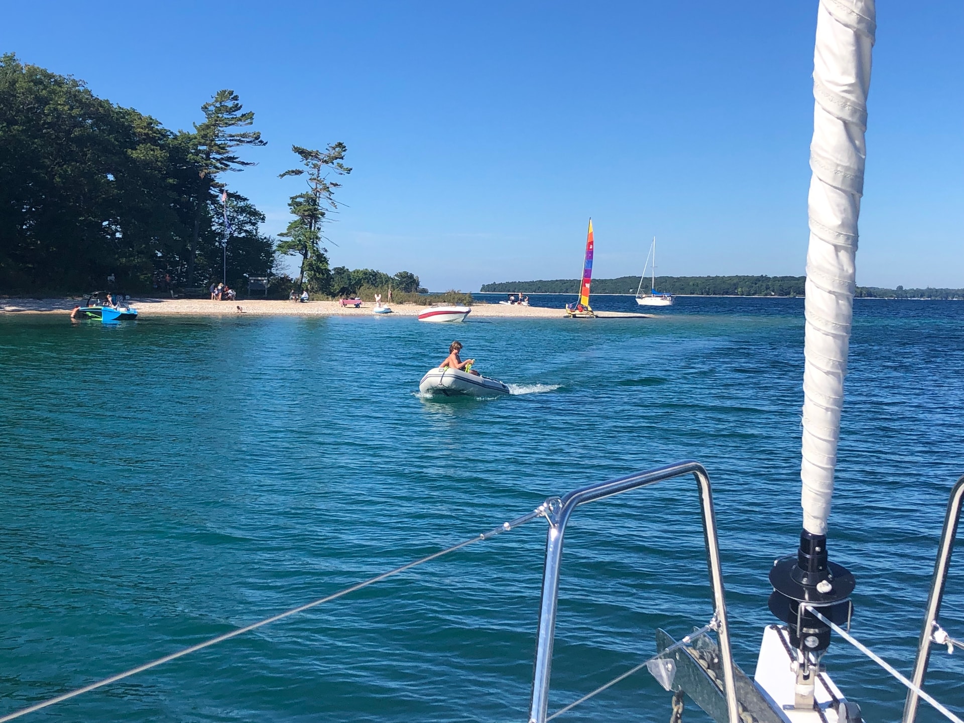 A picture of boats in the sea with a beach and trees in the background