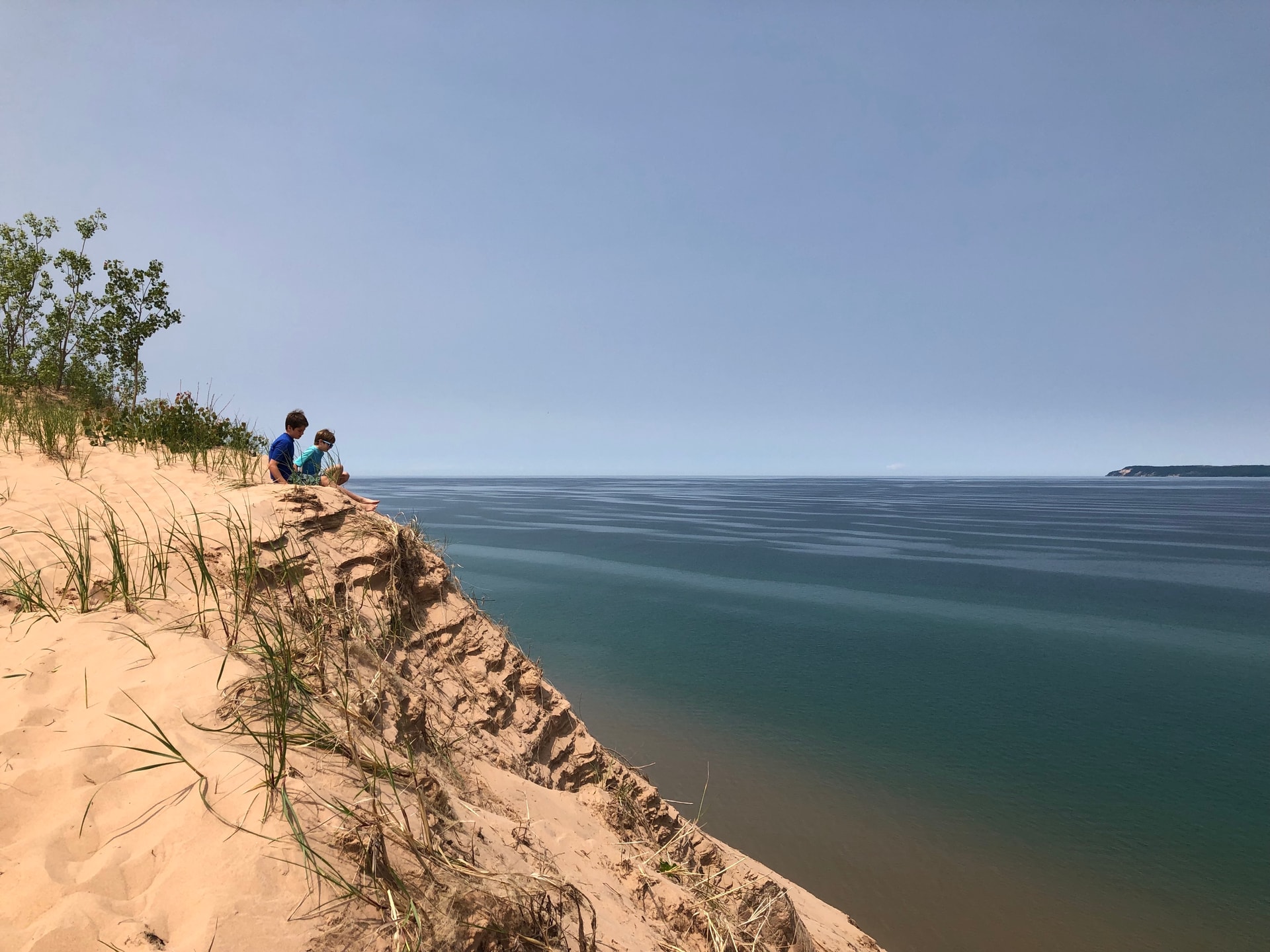 A picture of kids sitting on a cliff with a view of the sea