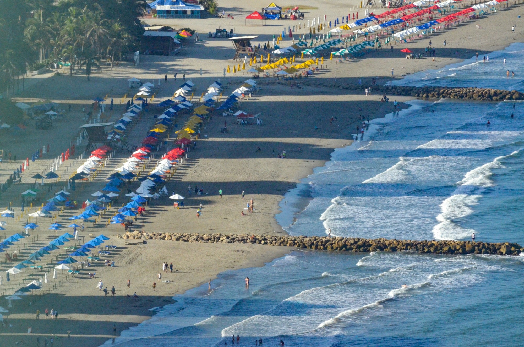 Aerial view of beach with beach umbrellas and people.