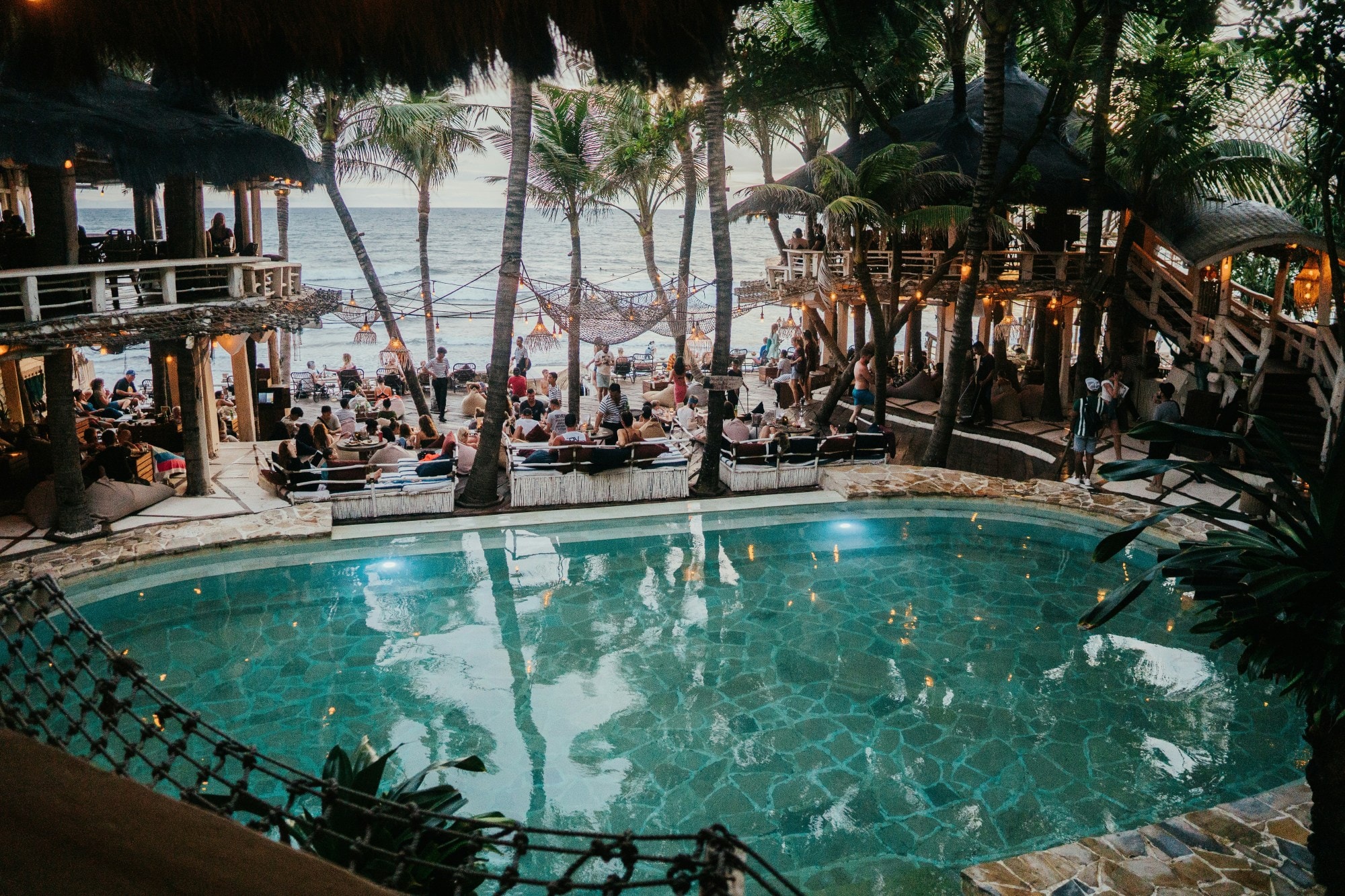 Beach club with pool, people and beach view. 