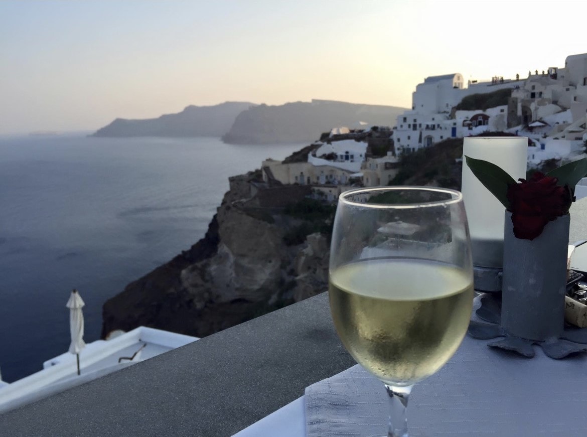 A wine glass with ocean and buildings at the back.