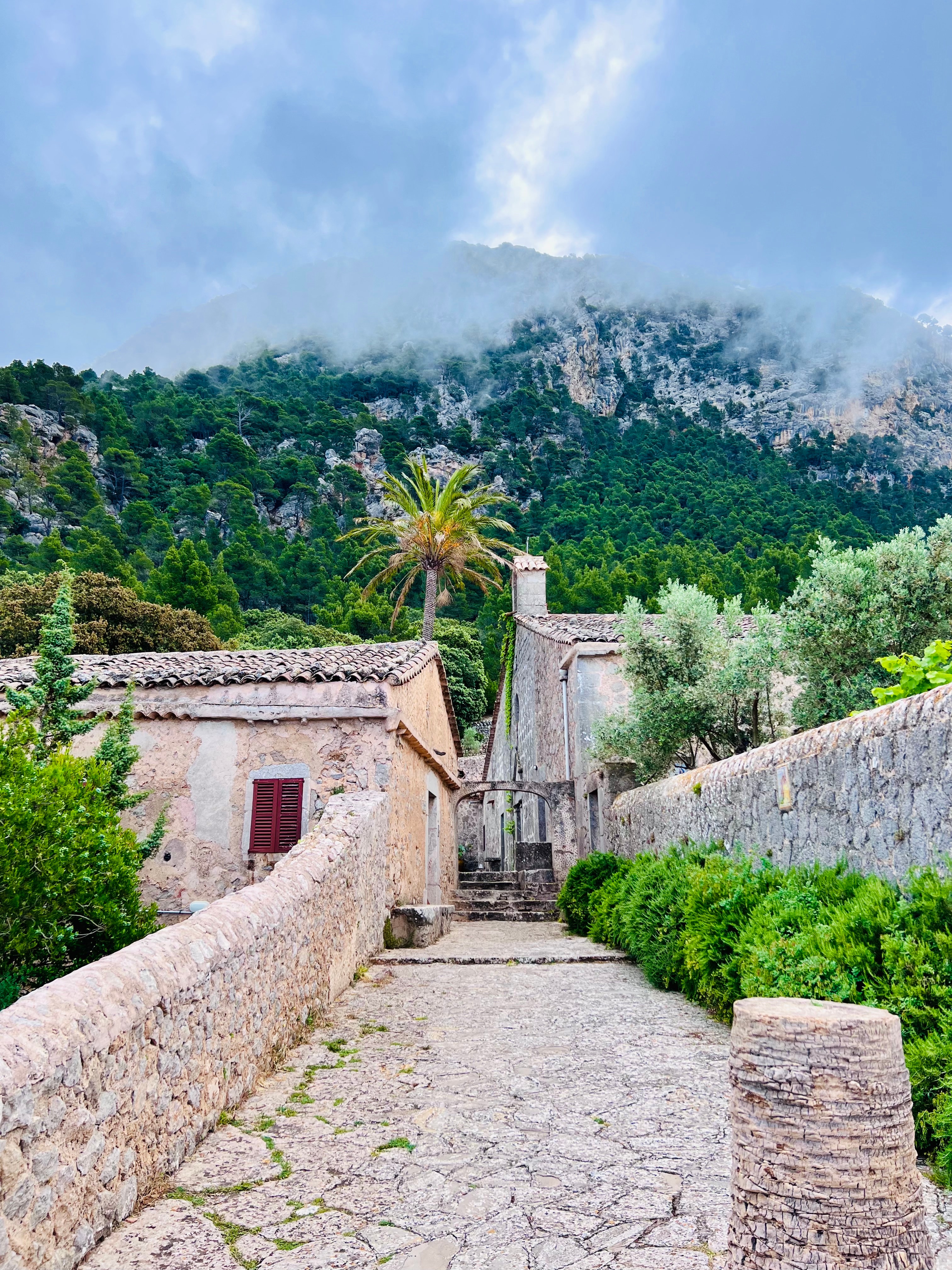 A cobblestone path leading up to a green mountain with clouds.