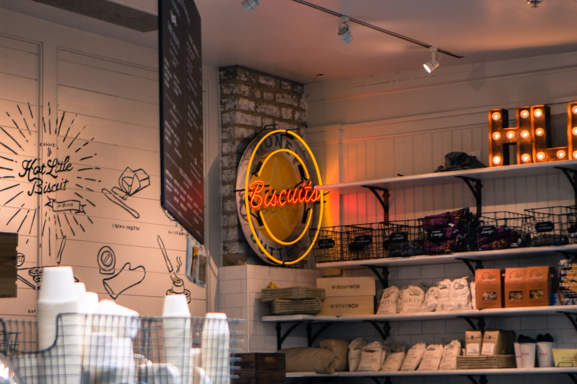 A cafe with coffee cups and a biscuits sign on wall. 