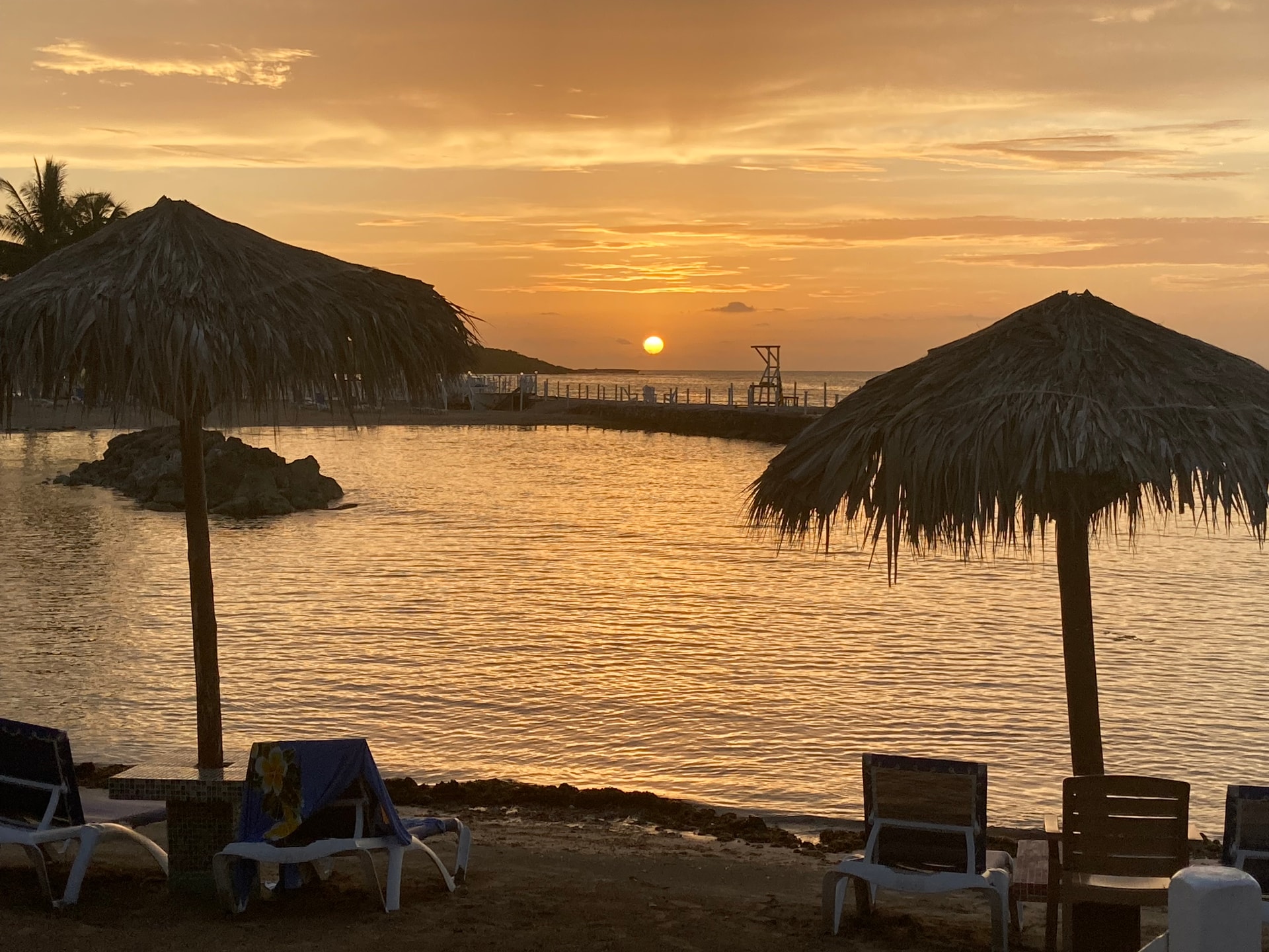 Sunset beach with tiki style umbrellas and relaxing lounge chairs.