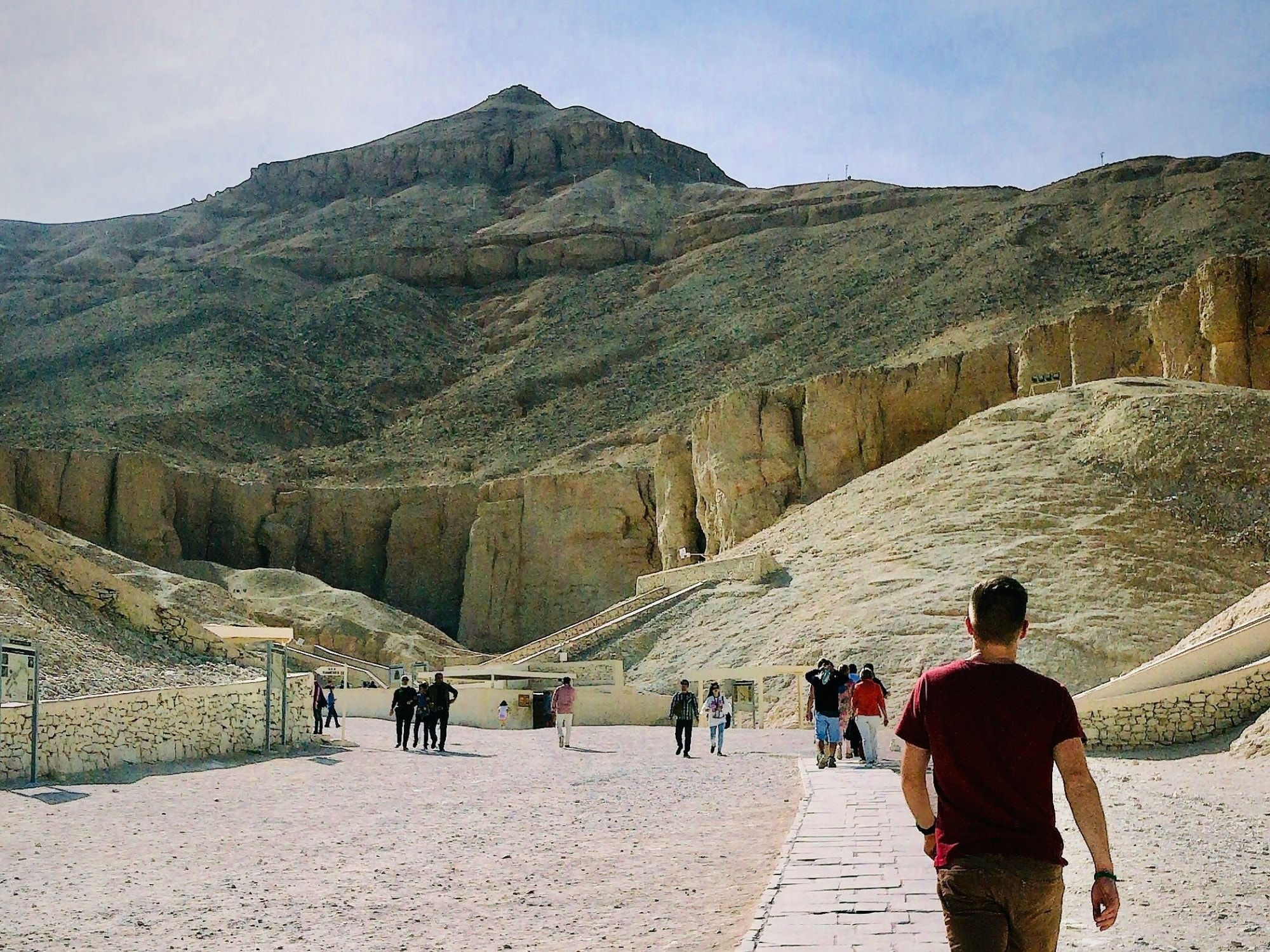 People walking on a path near rocky hills. 