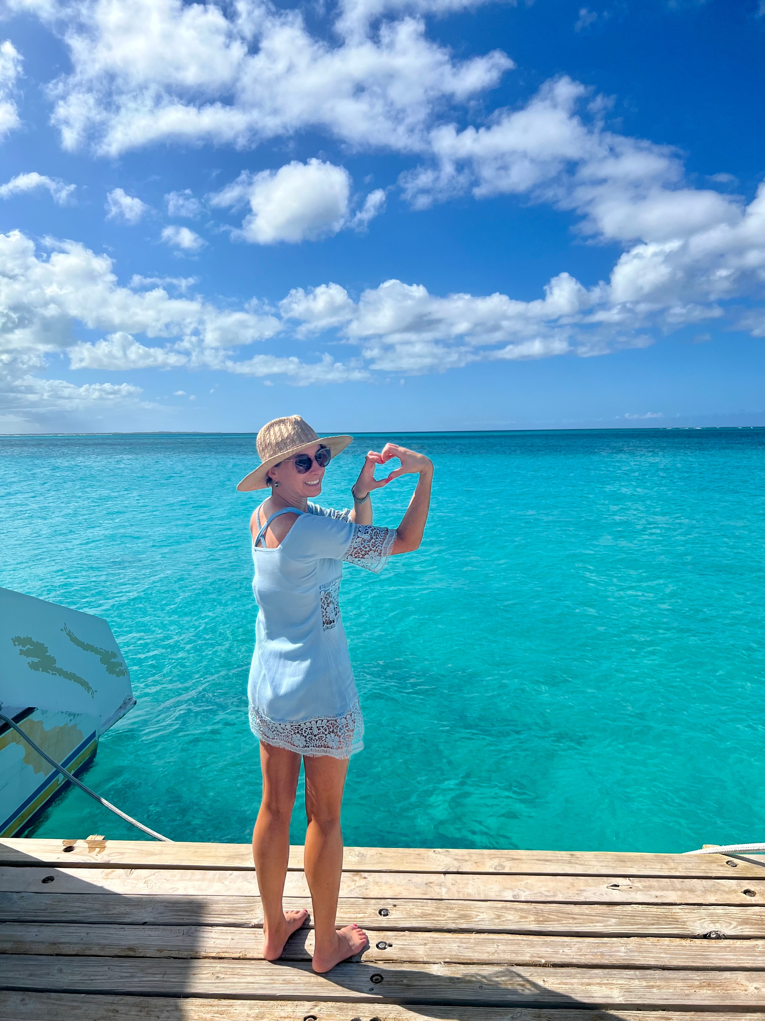 Travel advisor posing in front of clear blue ocean.