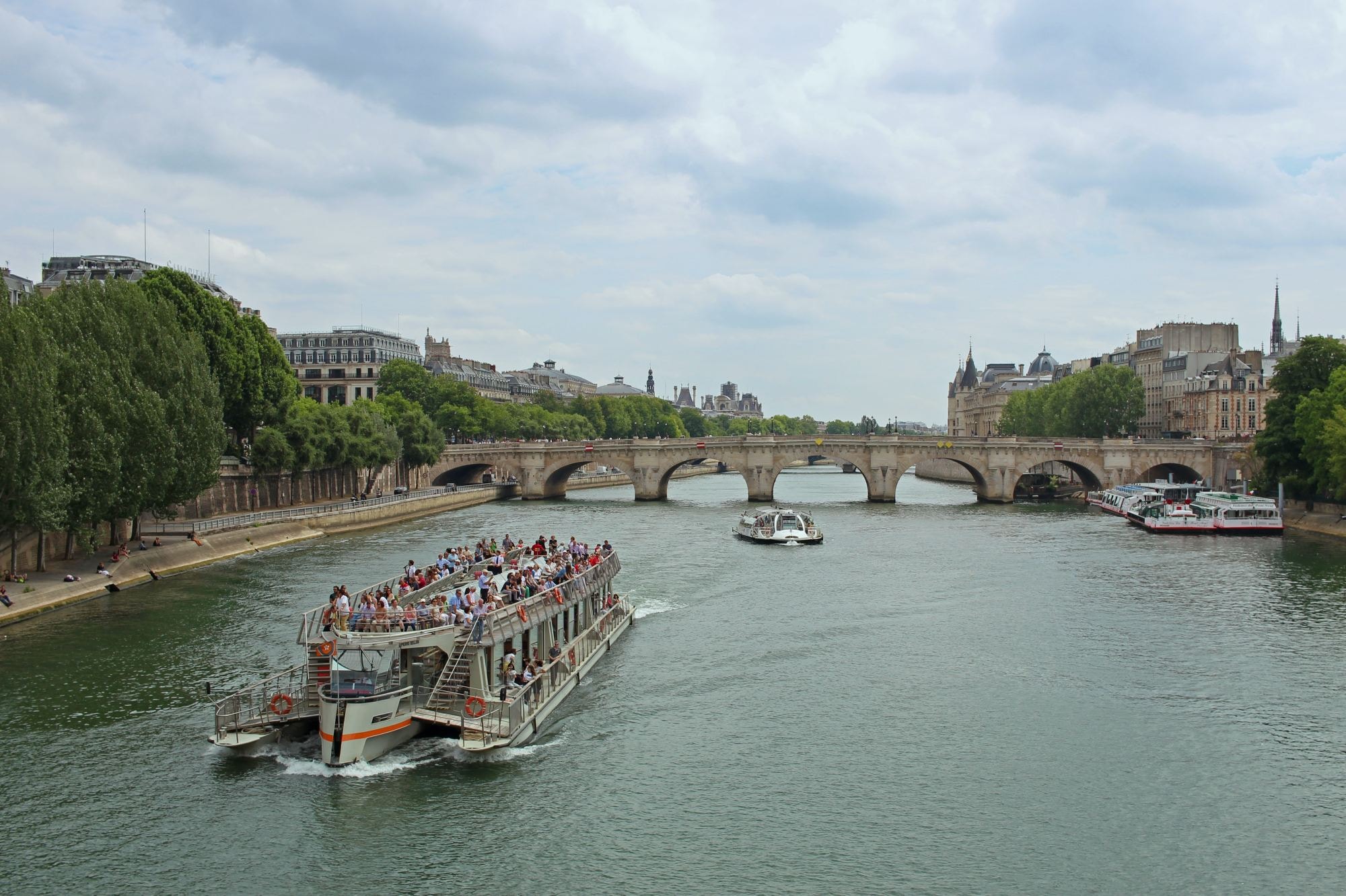 Cruise with people in a city canal on a cloudy day.