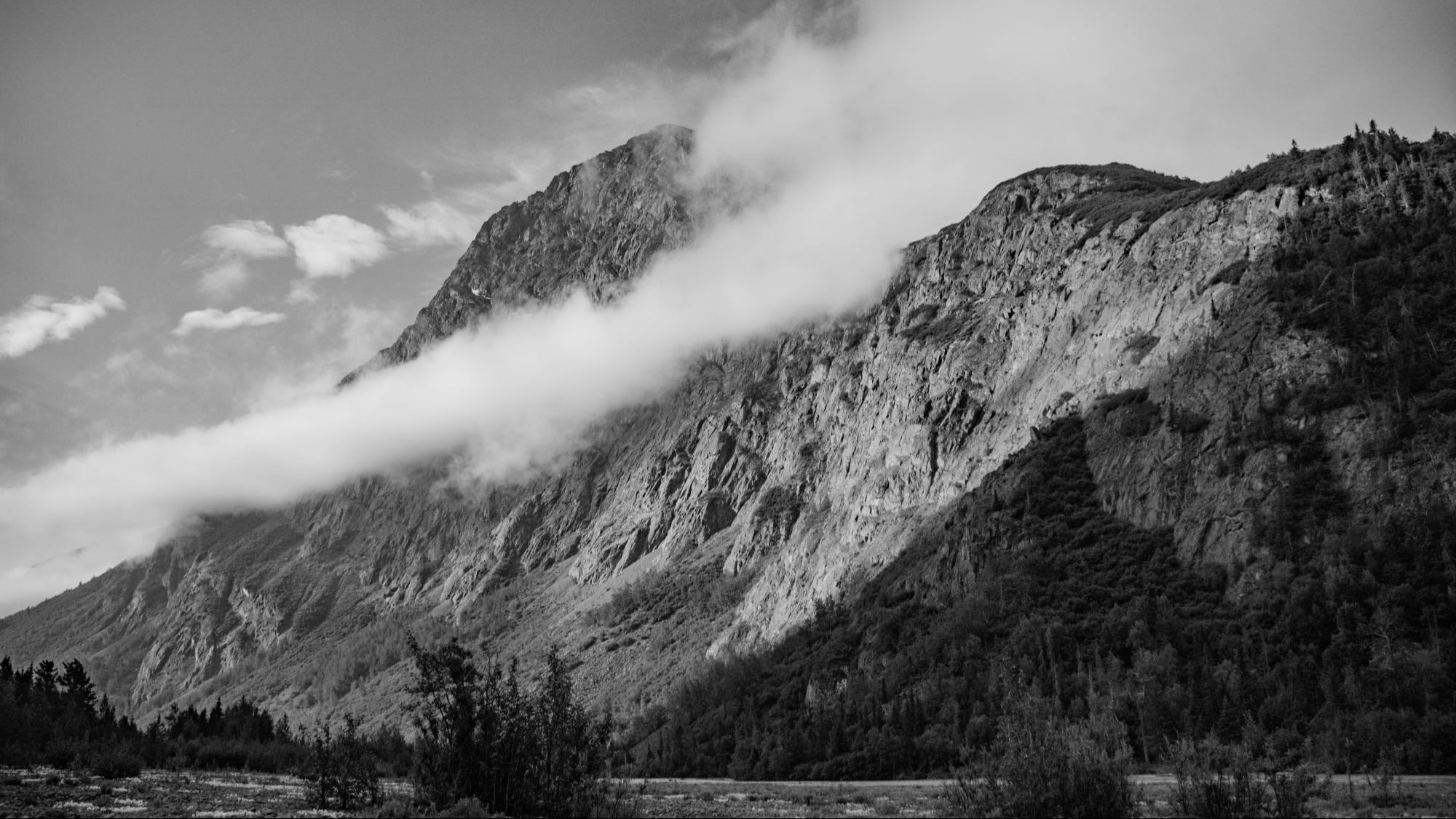 Black and white image of a large mountain with cloud. 