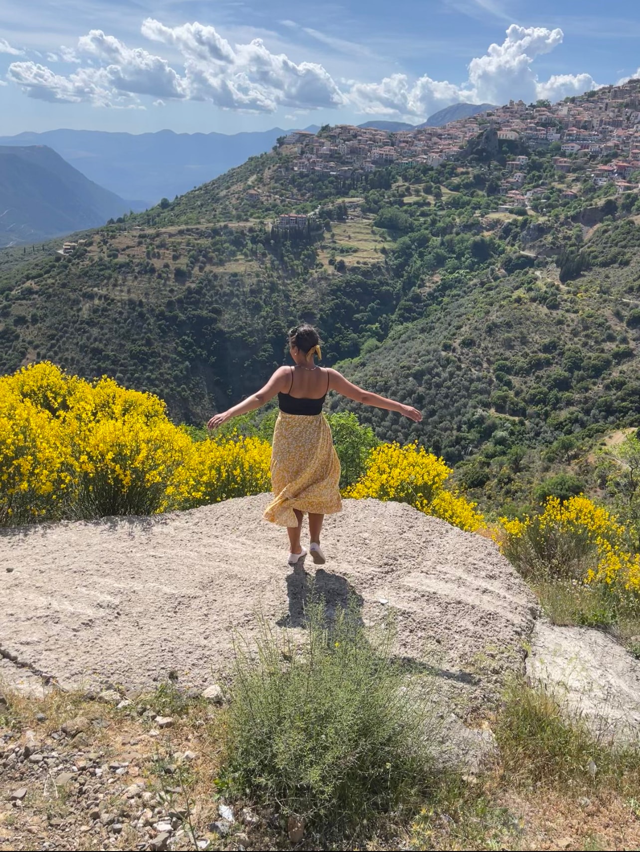 Travel advisor standing on a hill covered in yellow wildflowers overlooking a lush canyon.