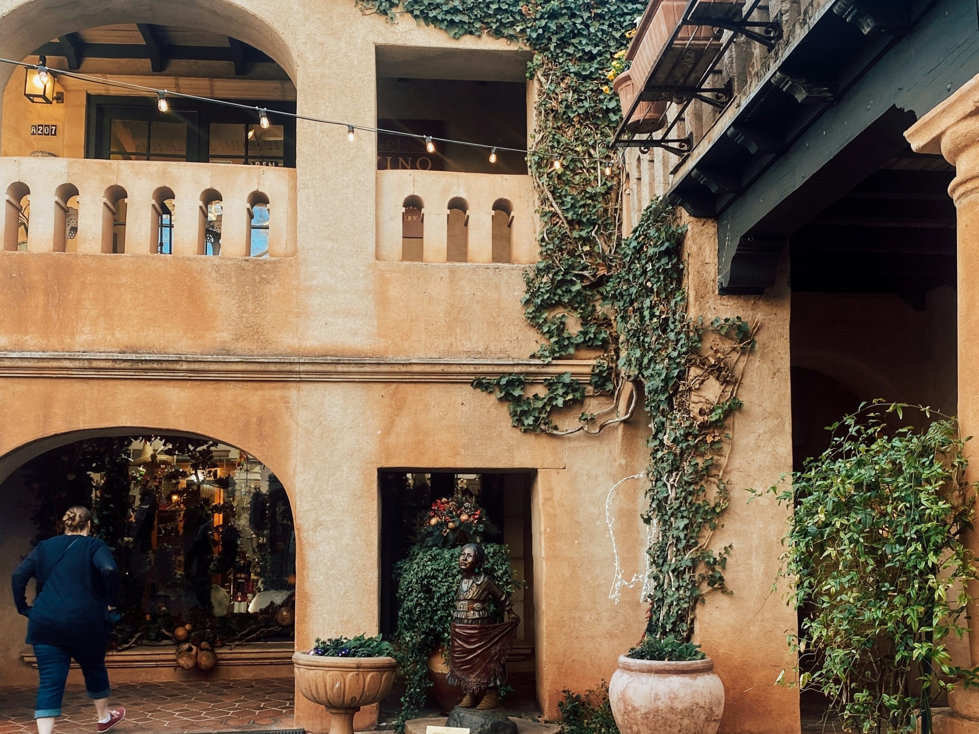 A woman entering a brown building with statue on side. 