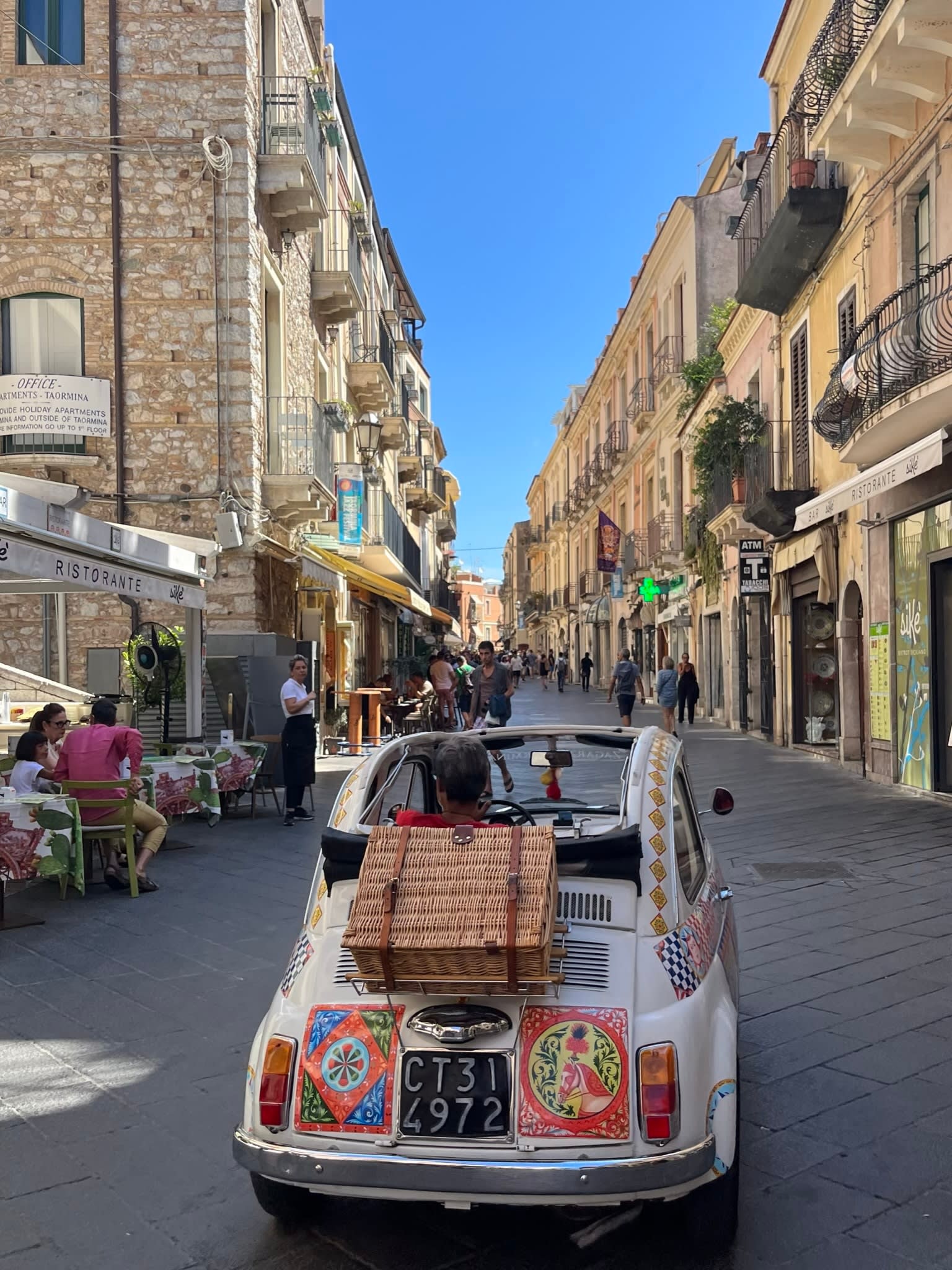 A painted VW bug car driving down a cobblestone street.