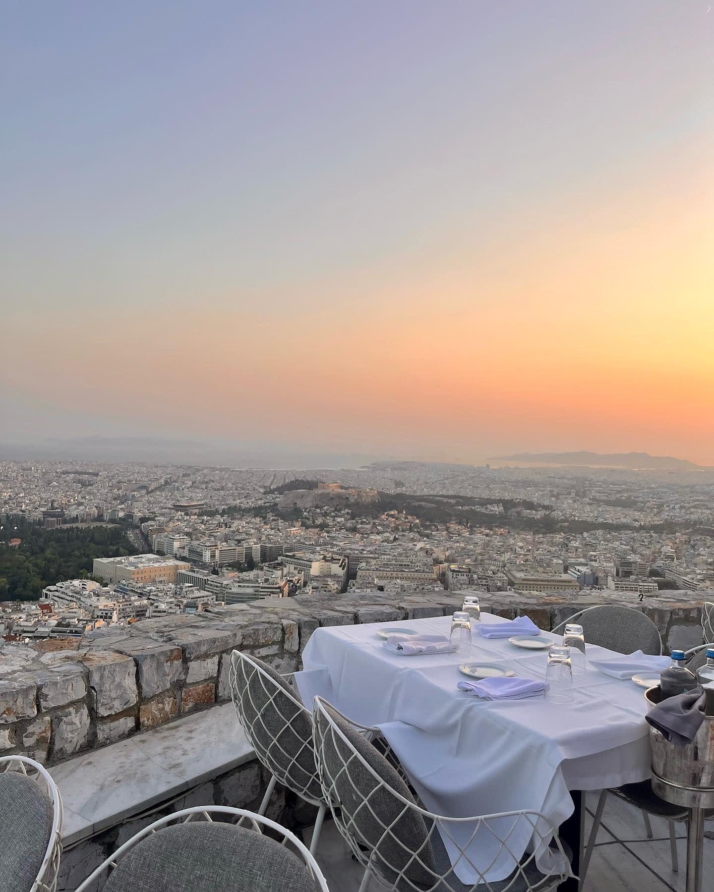 A restaurant patio overlooking a city at sunset.