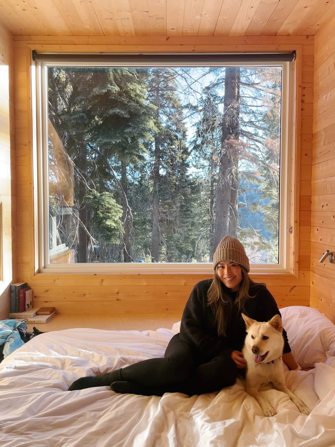 Advisor posing in a cozy hut with a dog and a nature setting outside. 