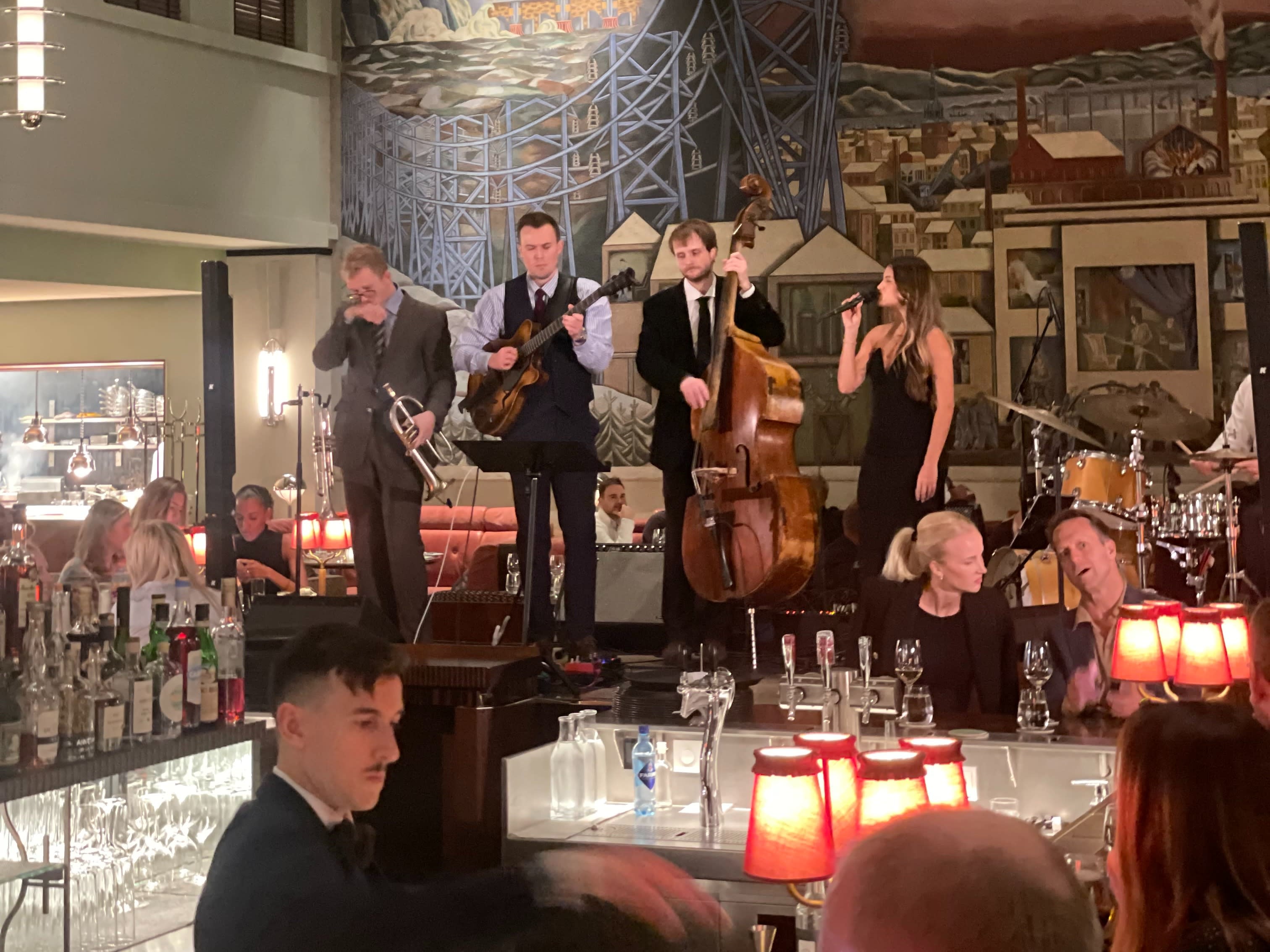 A lively restaurant filled with patrons at tables as a band plays on stage.