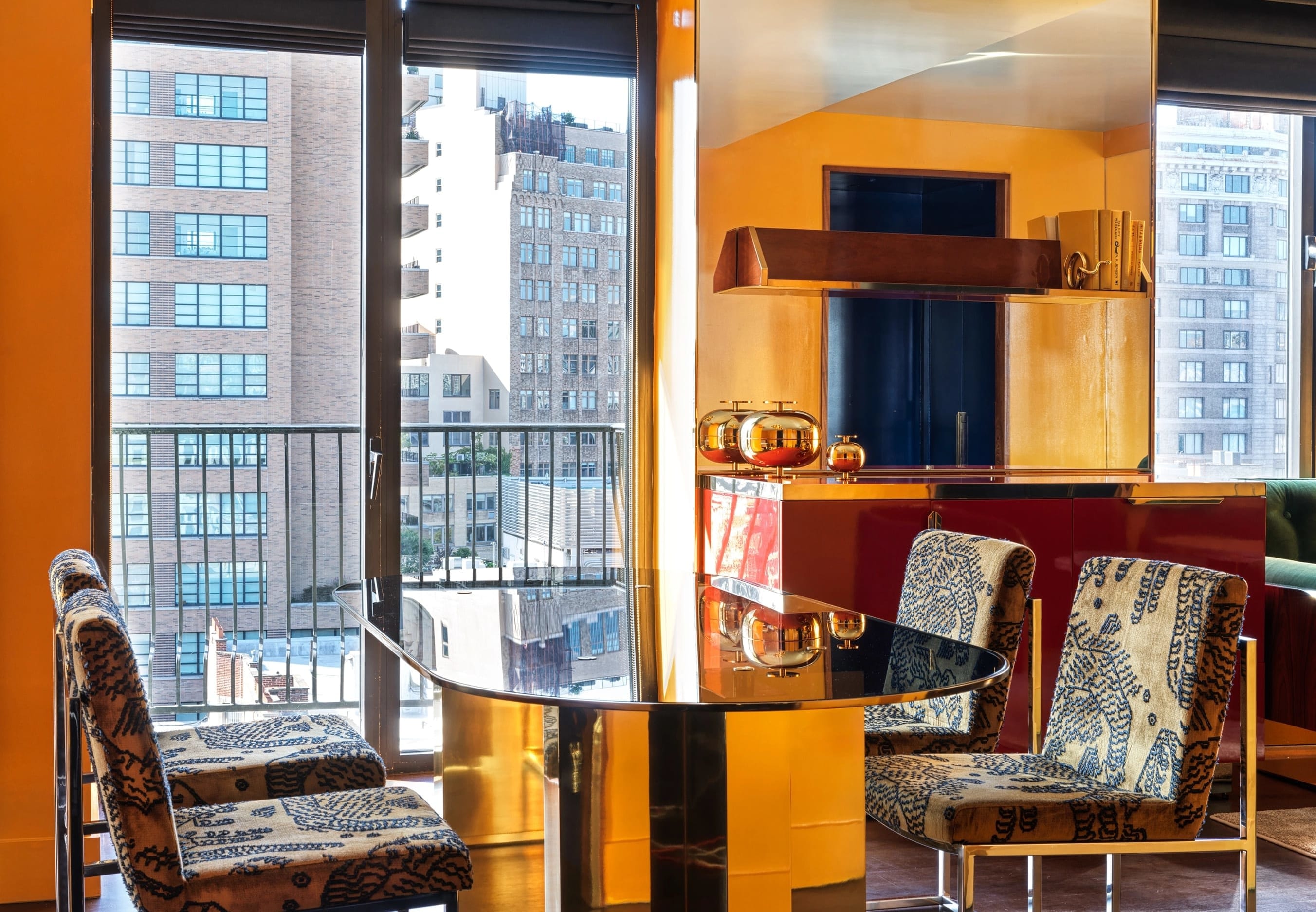 a dining area in a hotel room with a bronze reflective table surrounded by patterned chairs