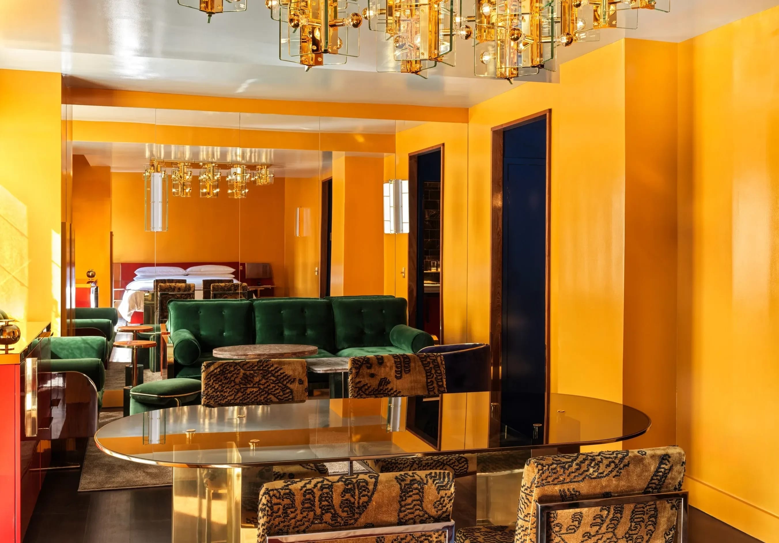 a yellow-walled hotel room with a green couch and a gold table