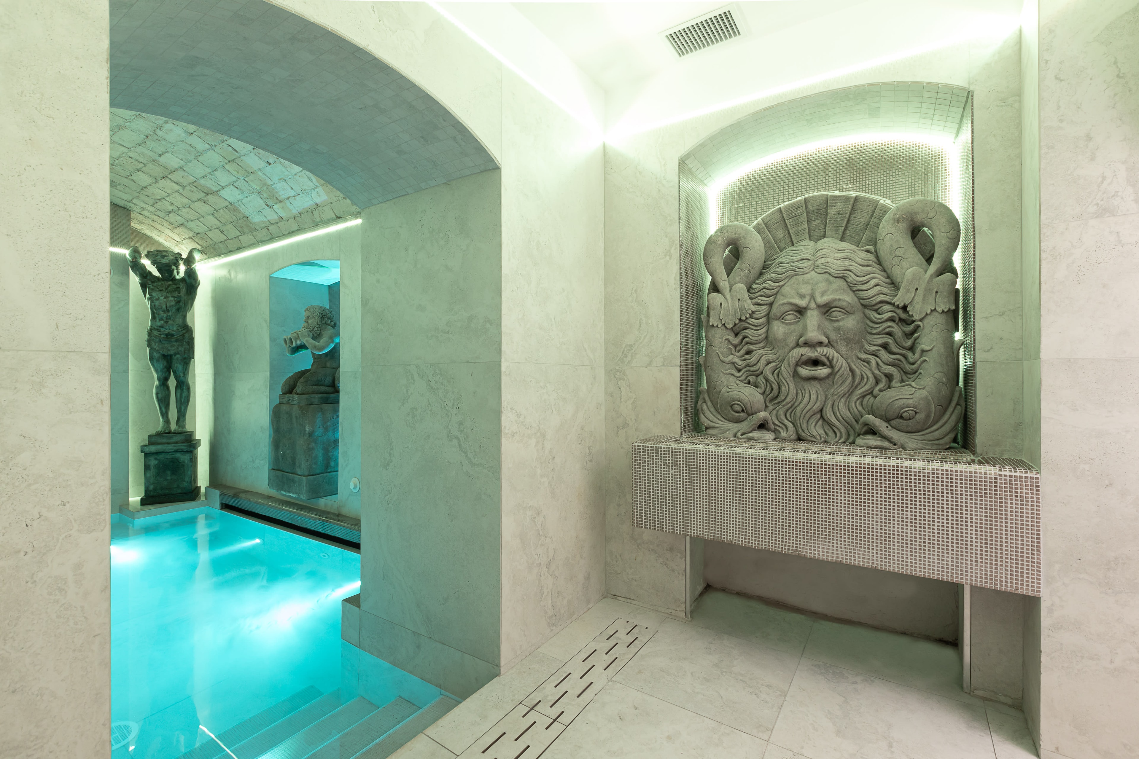 an indoor pool with stone statues