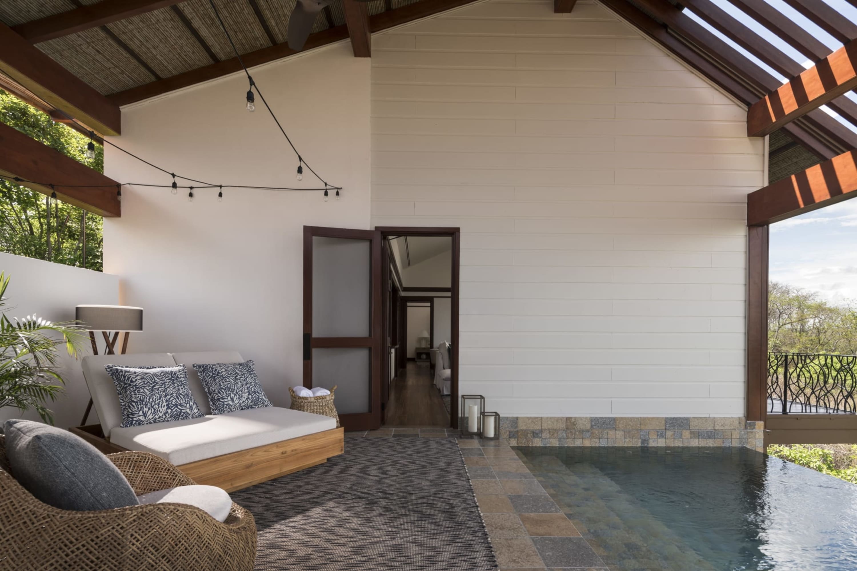 Twin outdoor sofas sit under an awning on a chic outdoor space that also includes a private plunge pool