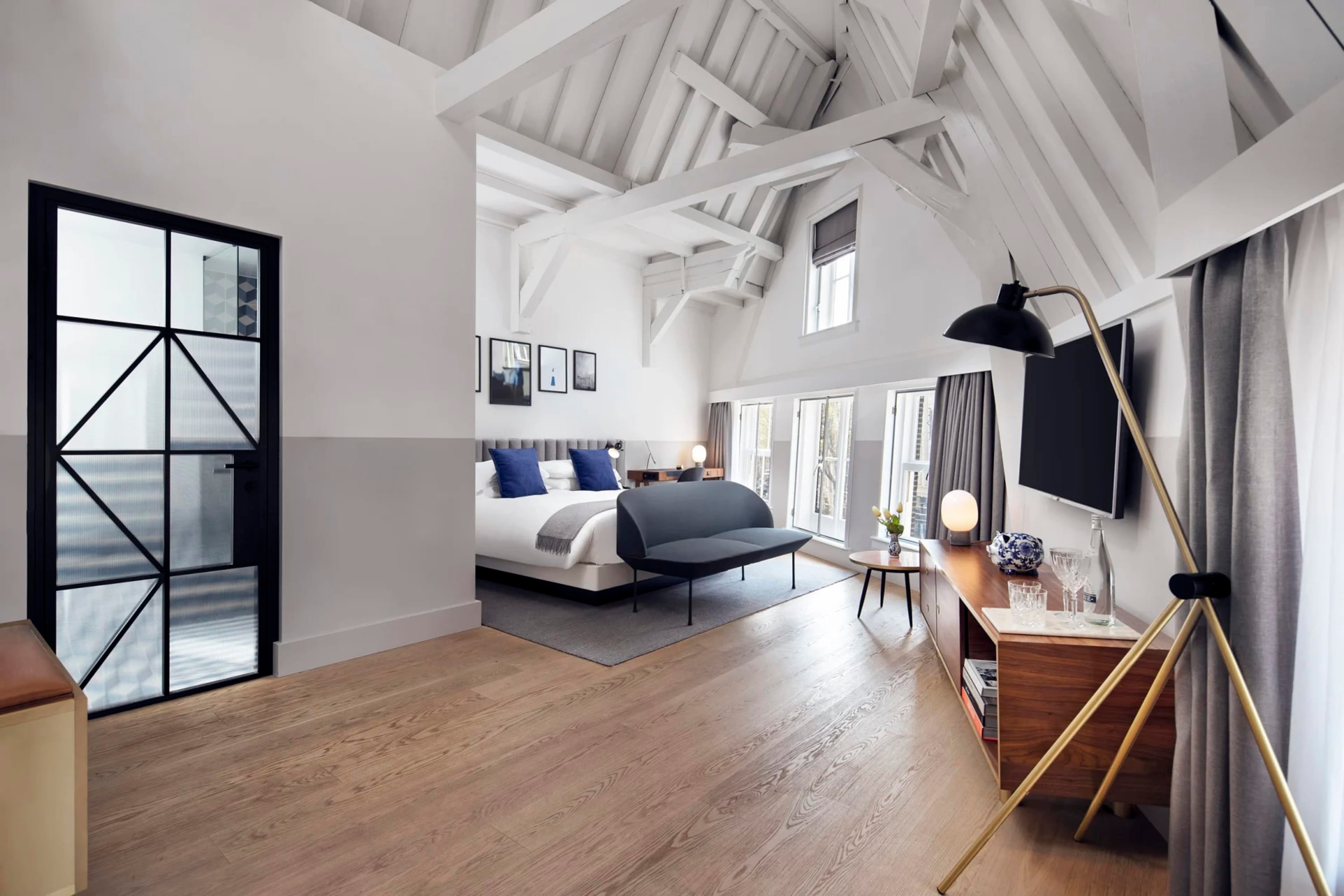 Chic contemporary furniture in a spacious room with hardwood floors and exposed support beams. The room layout is trapazoidal rather than rectangular