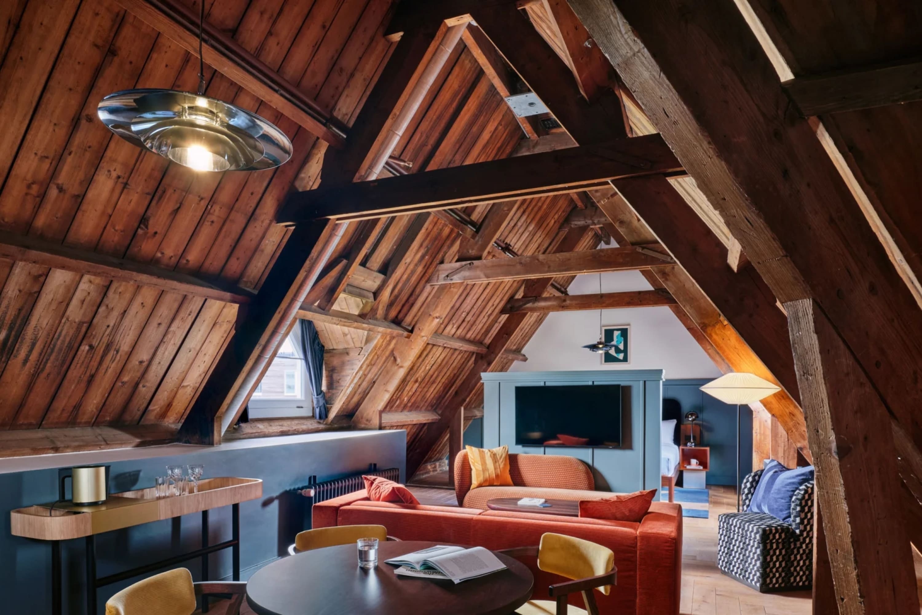 Bold colors stylishly clash with a wooden vaulted ceiling in a cozy common space at The Hoxton, Lloyd Amsterdam