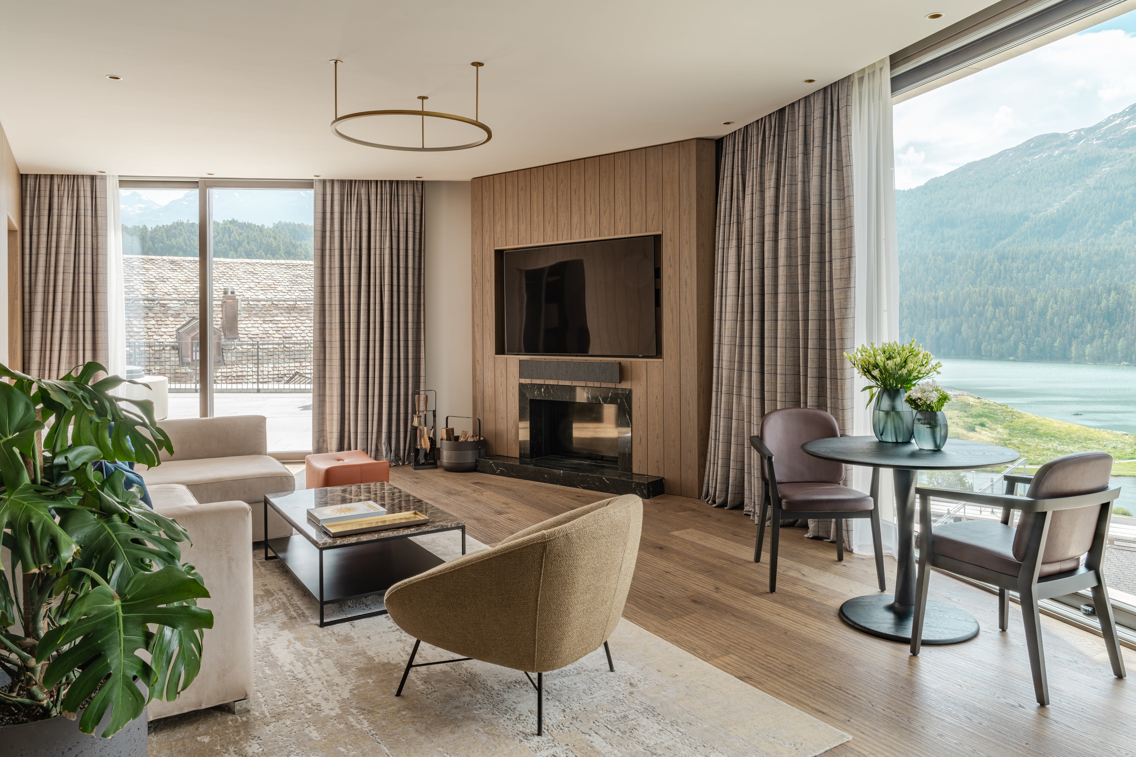 a hotel living room with large windows framing Alpine views