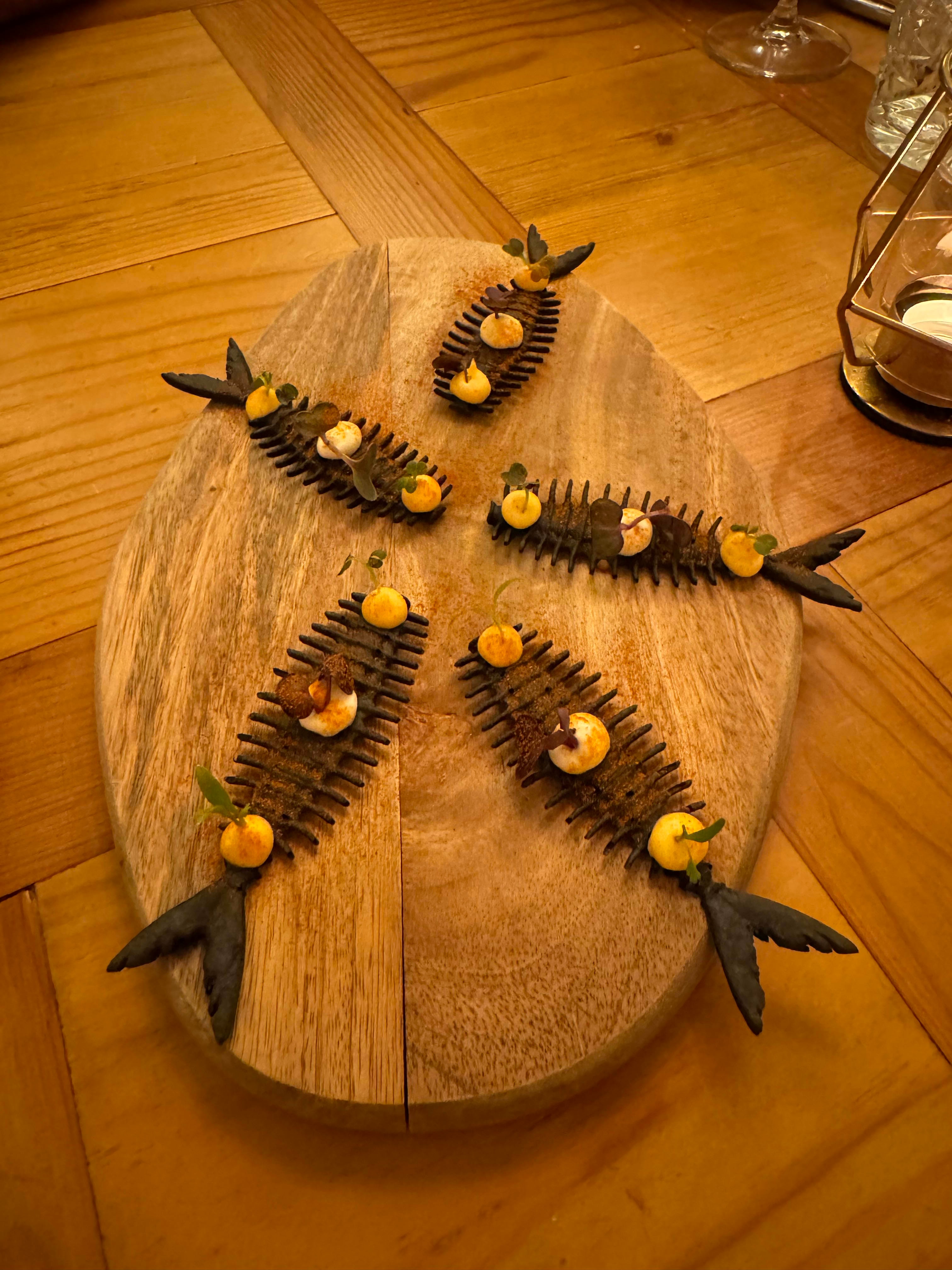 An artfully arranged appetizer sits a top a cutting board and hardwood table.