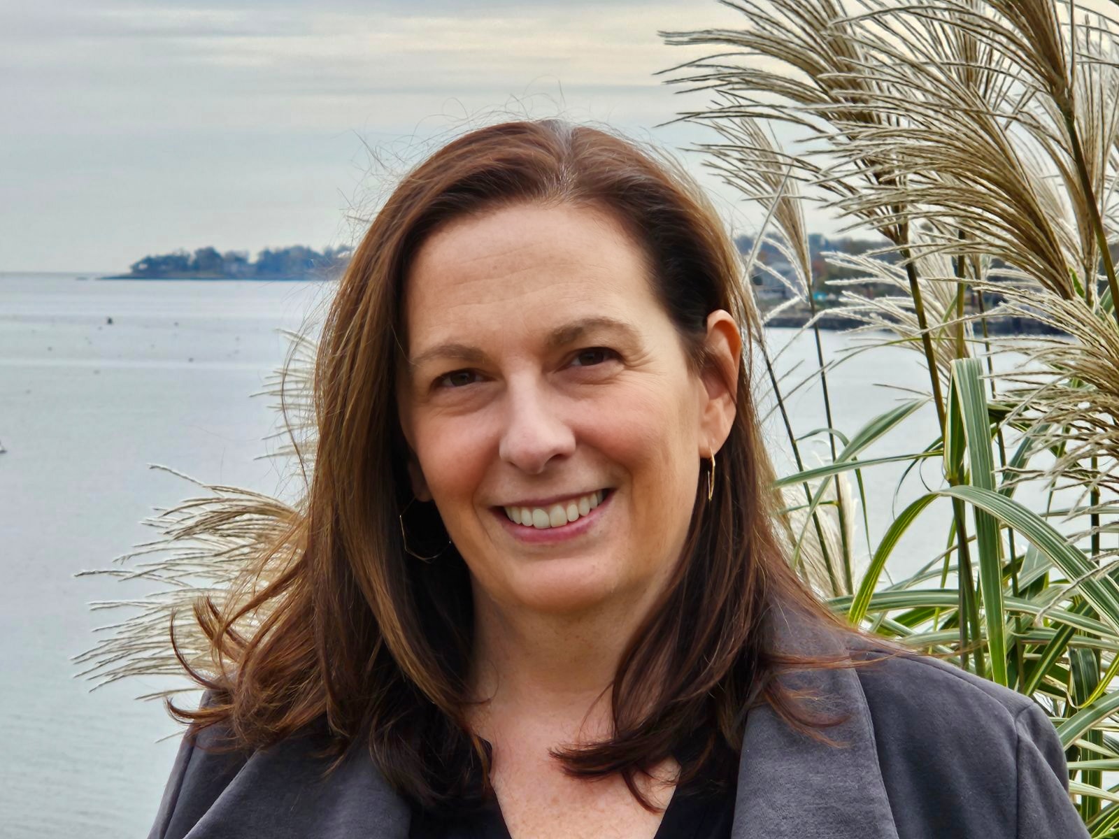 Travel Advisor Nicole Freedman in a black sweater with a blue and white map behind her.