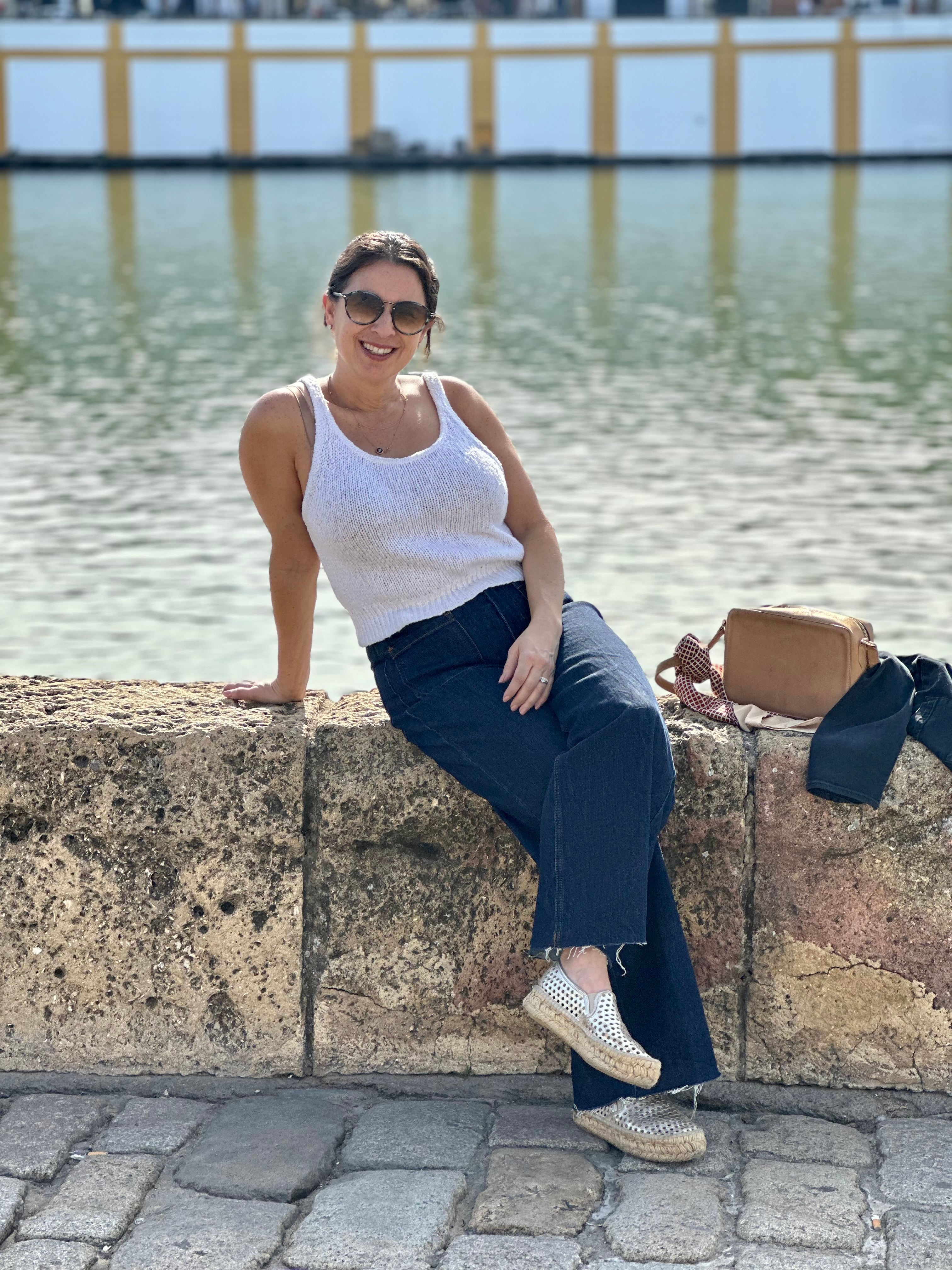 Advisor sitting on a stone ledge in front of a body of water on a sunny day