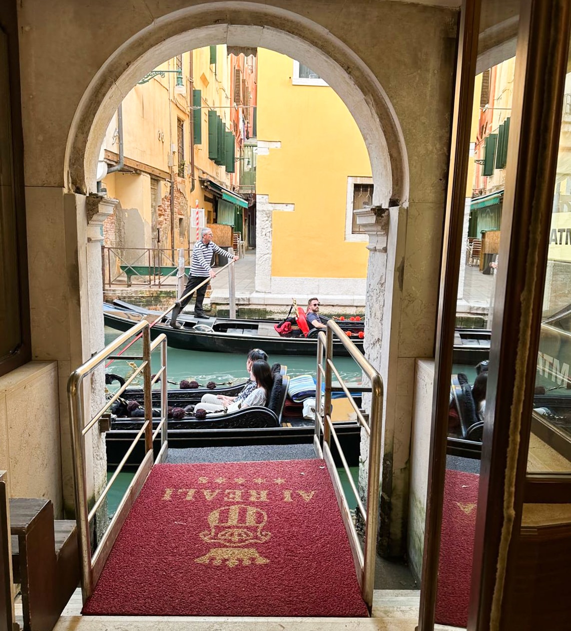 A view from the entrance of a hotel onto a canal with gondolas