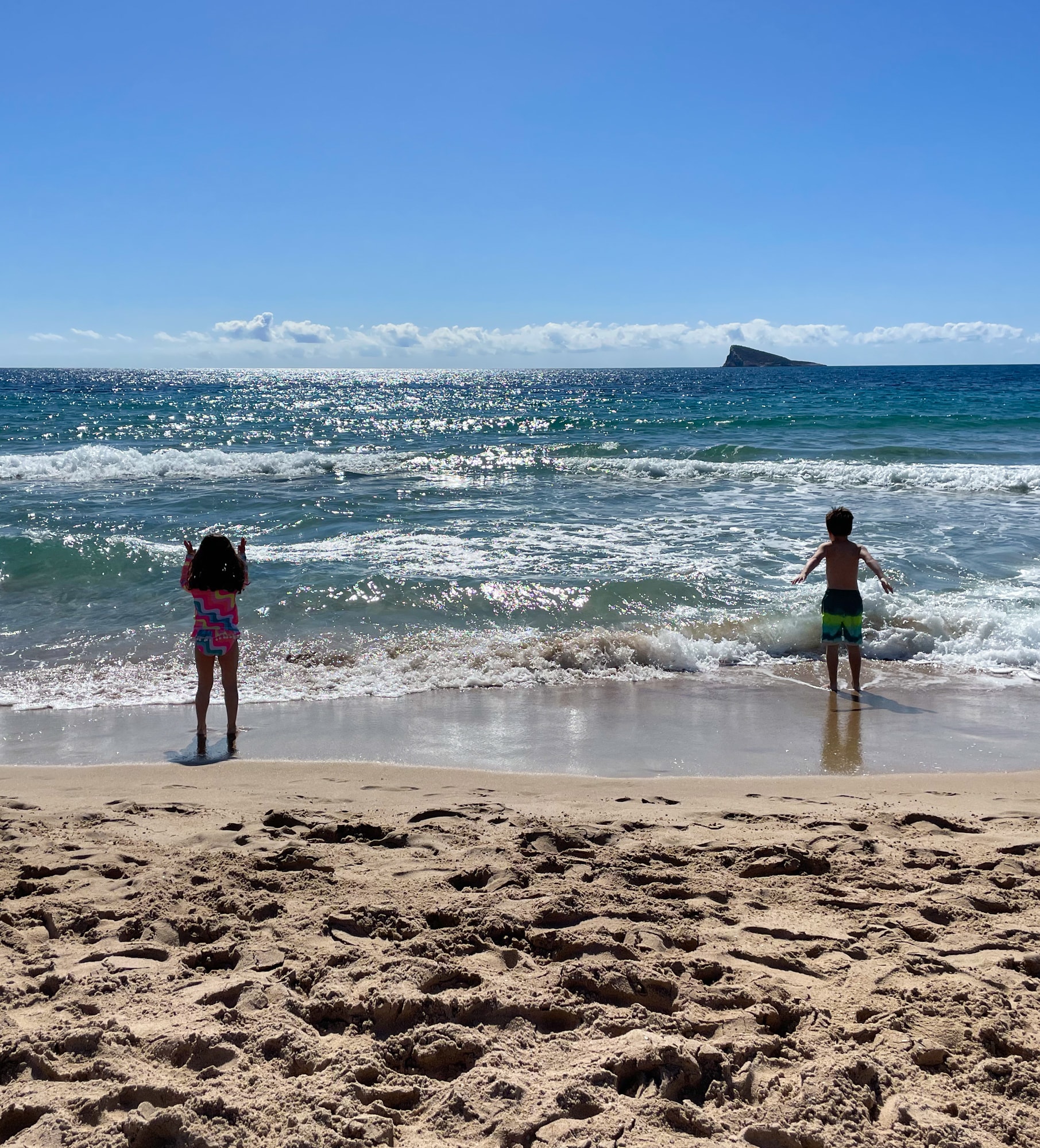 Two children playing on the beach on a sunny day