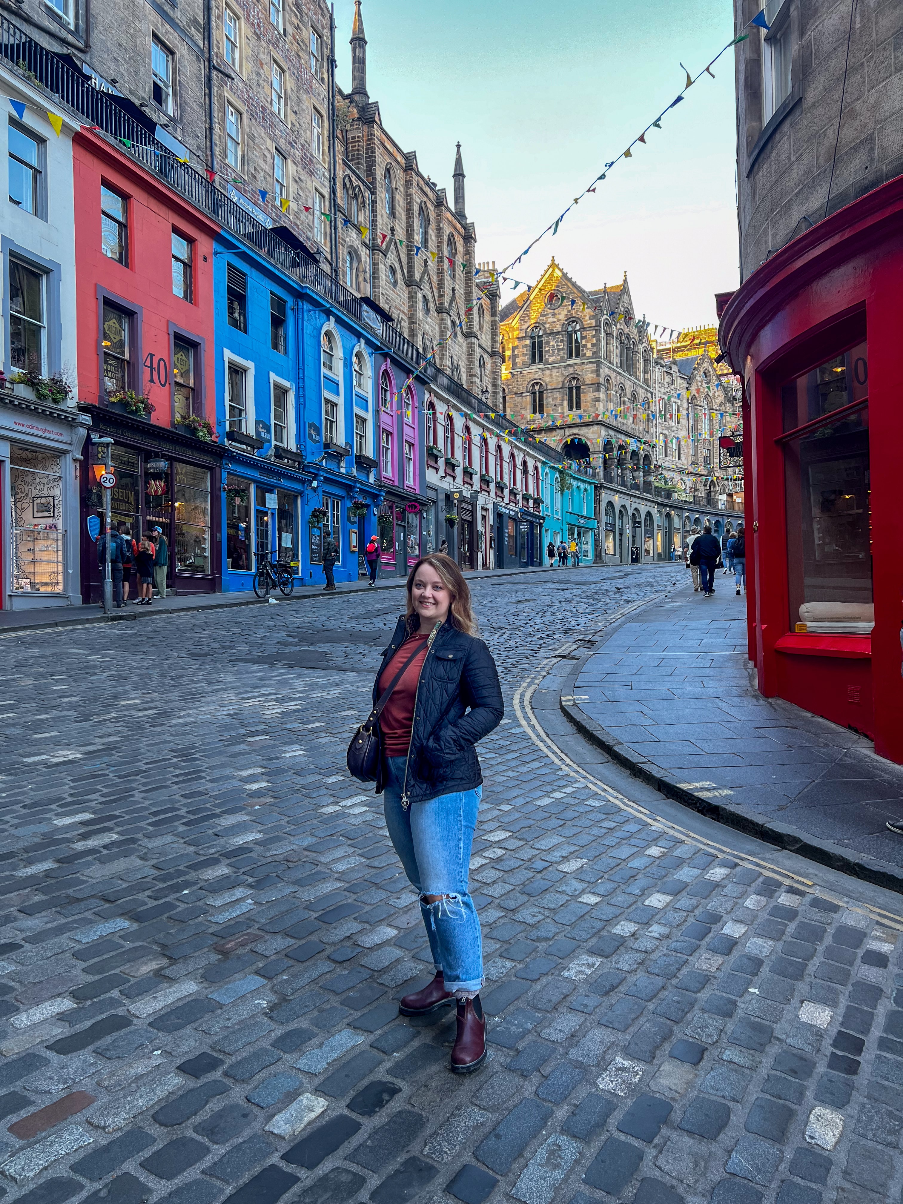 Advisor posing for an photo in a town square with colorful buildings at dusk. 