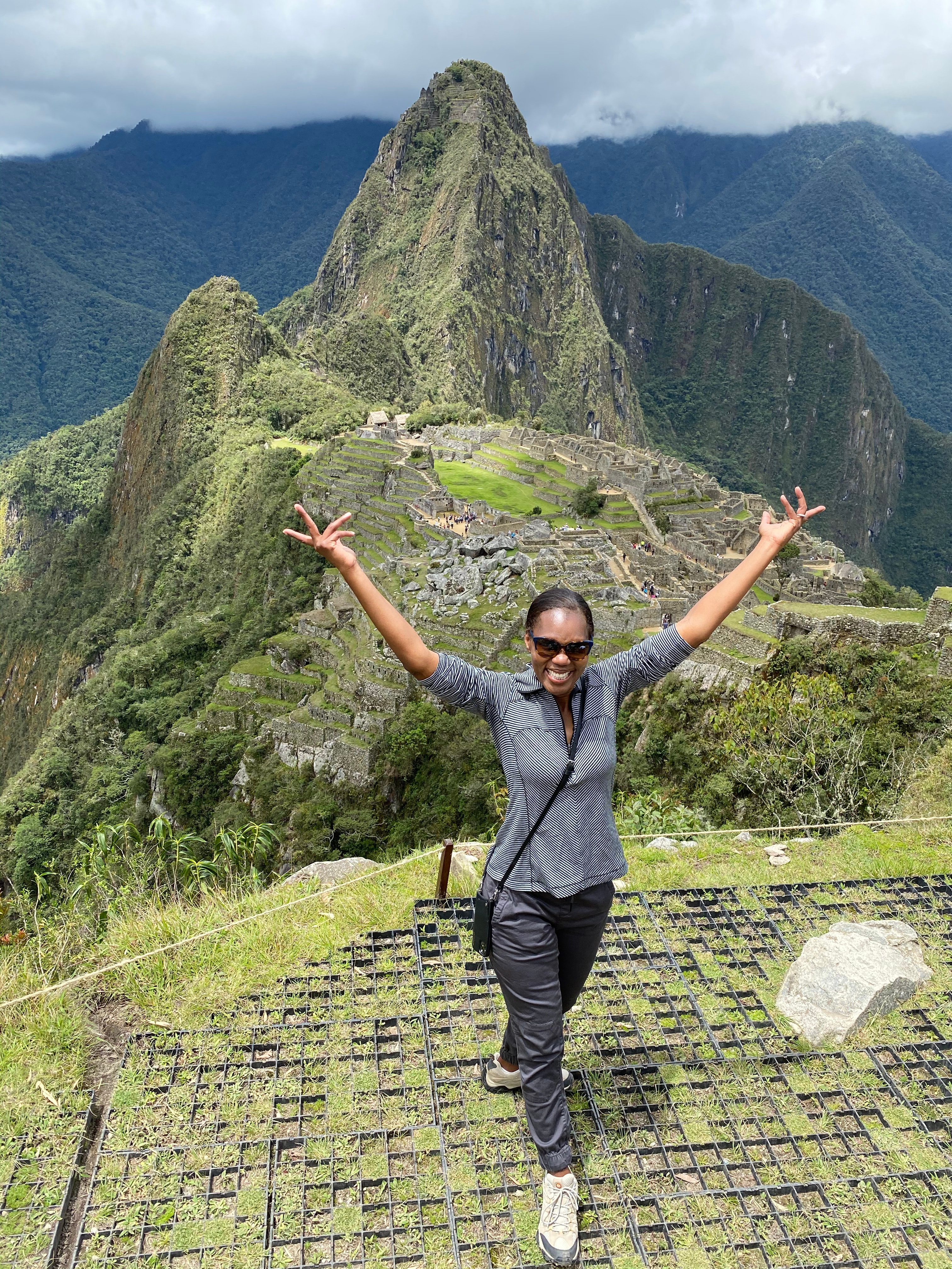 Advisor on a hike at the top of a mountain with large cliffs in the distance covered in foliage.