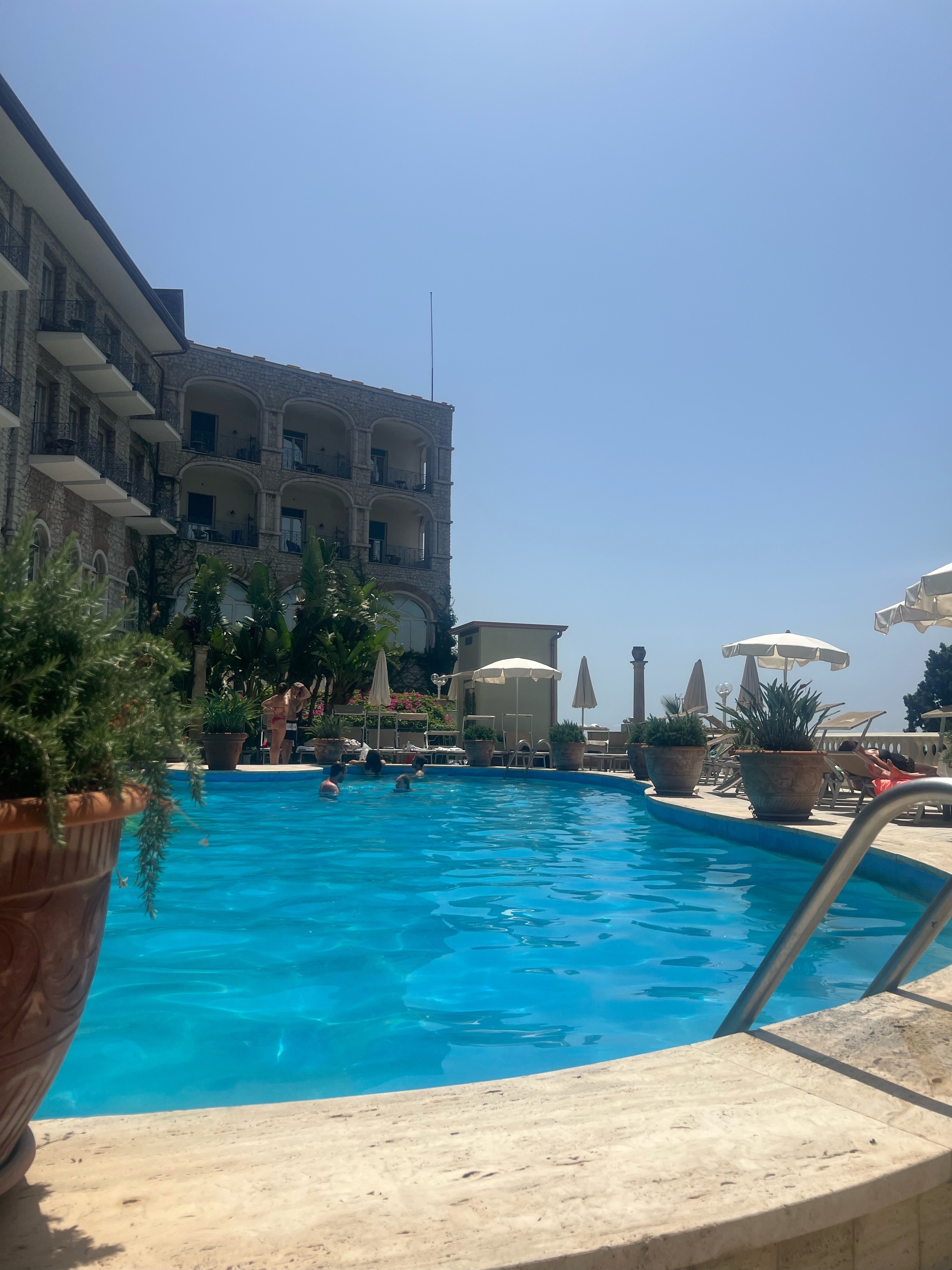 A beautiful view of a pool with the hotel in the background on a sunny day. 