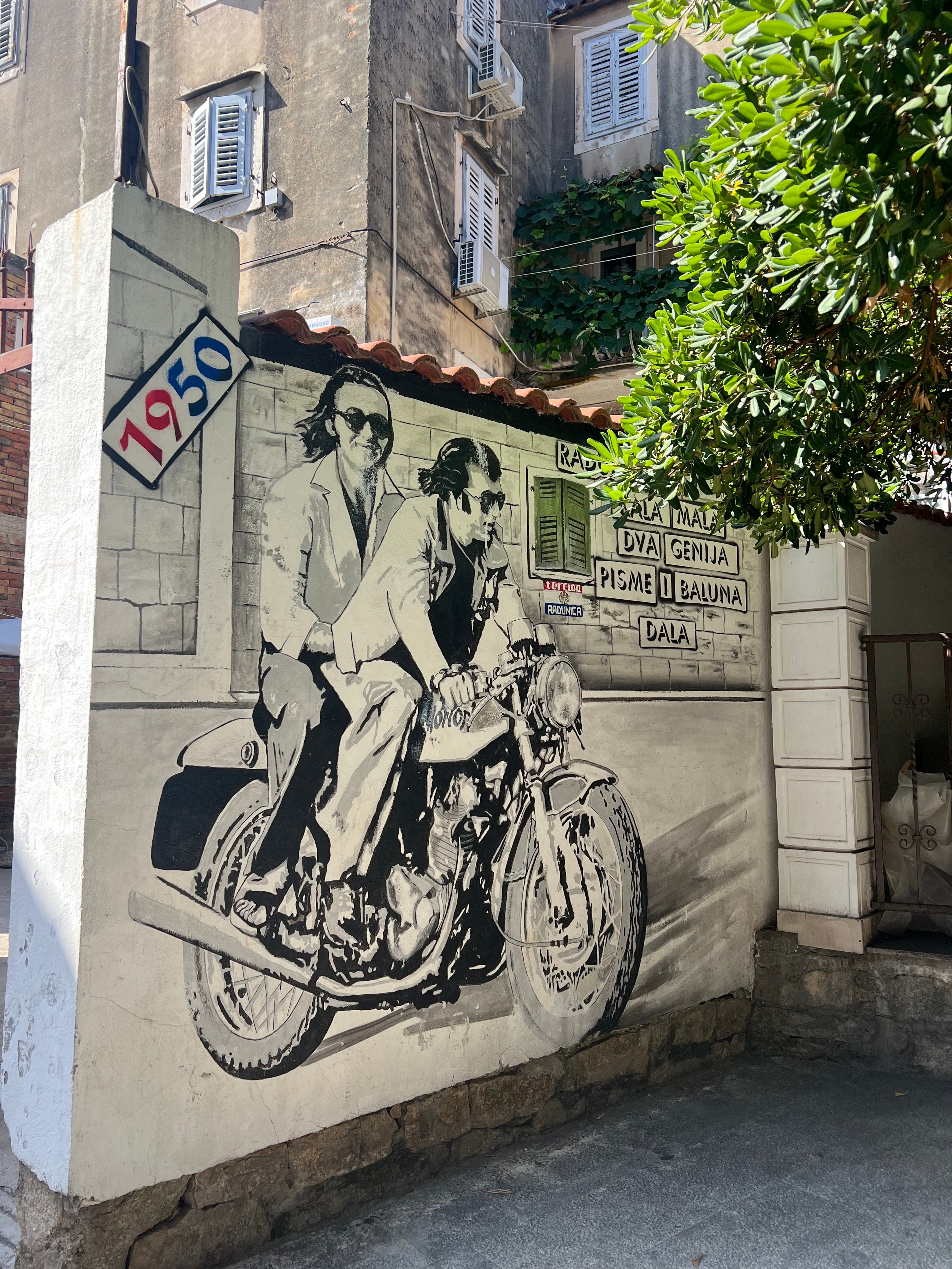 Street art of two people on a motorcycle in 1950 driving through the streets of Split, Croatia. 