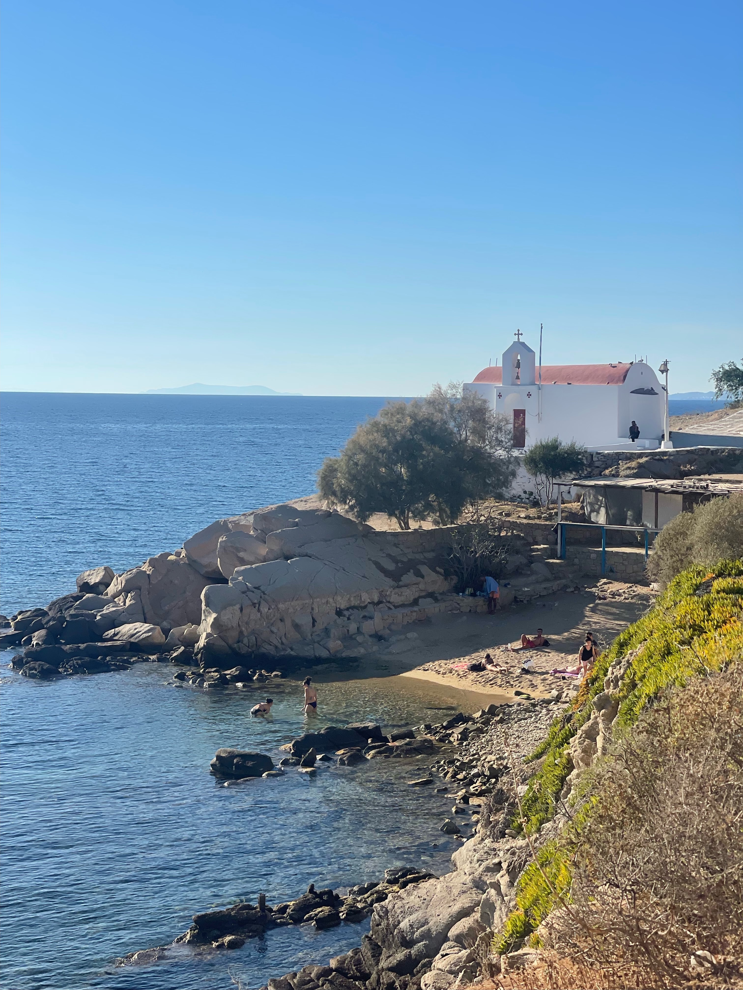 A beautiful view of an ocean cliff with a church in the distance on a sunny day. 