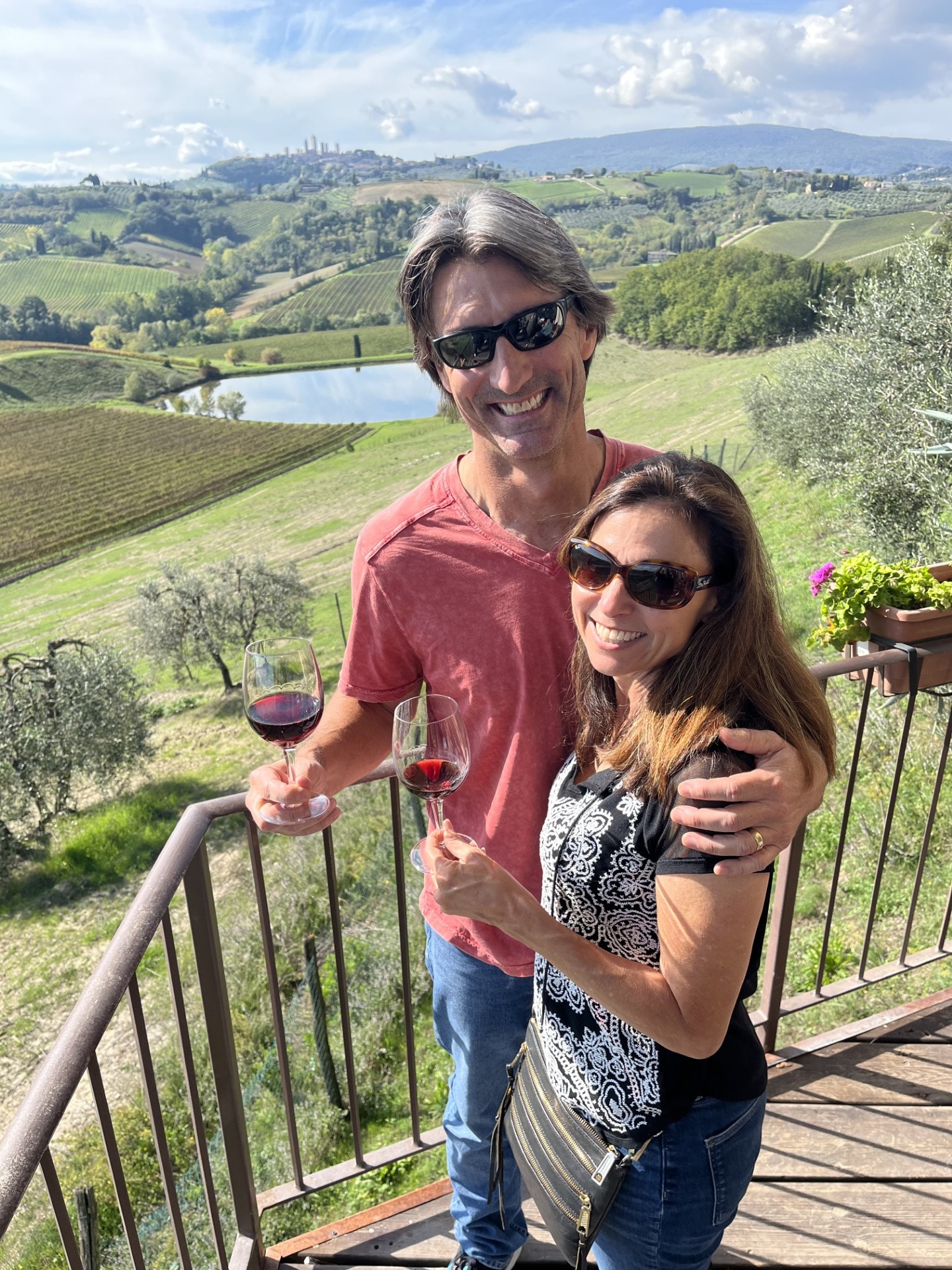 Kristine and a man standing on a balcony overlooking a Tuscan vineyard.