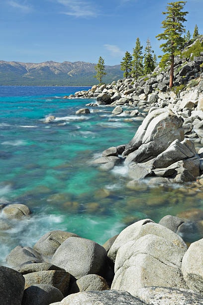 A lakeshore with rocky outcroppings and evergreen trees.