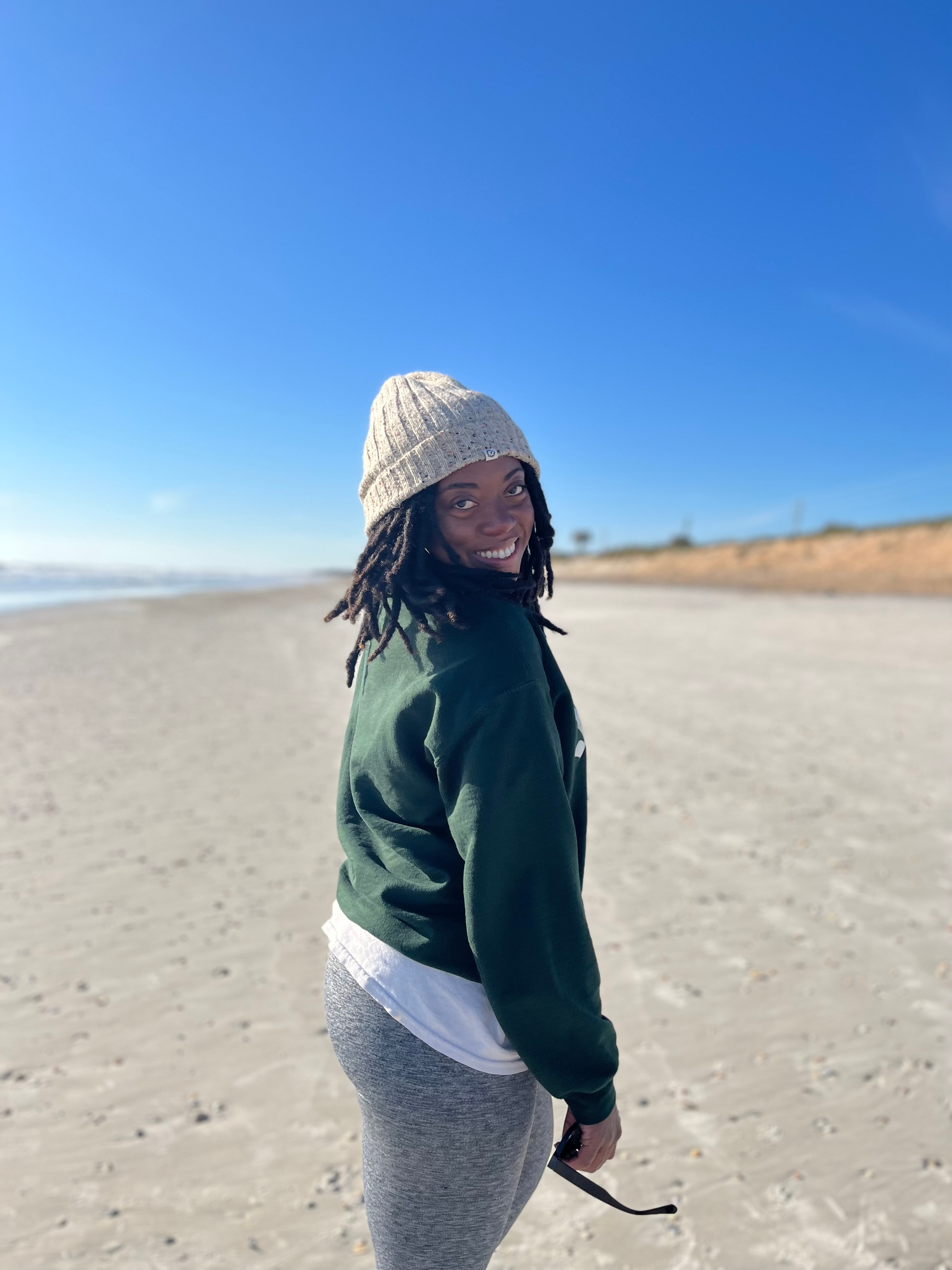 Ashlyn in a green sweatshirt on the beach.