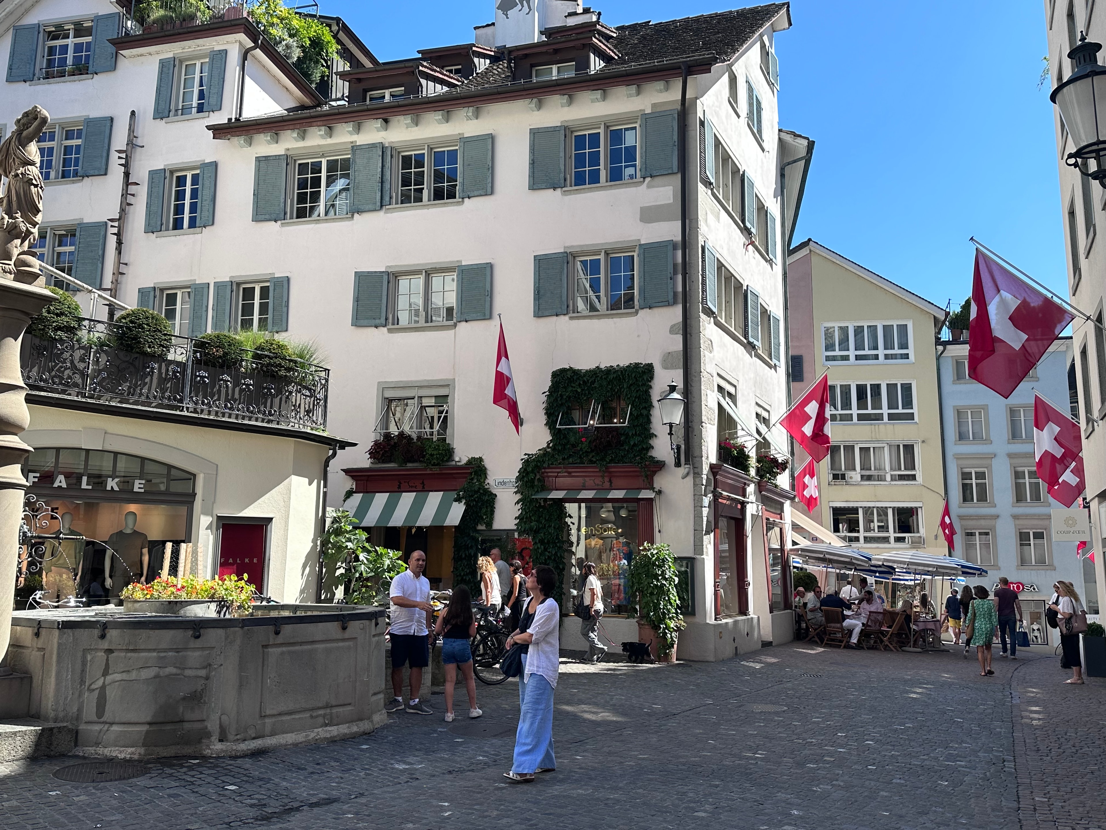 A beautiful view of a town with the sun shining and people walking in the streets. 