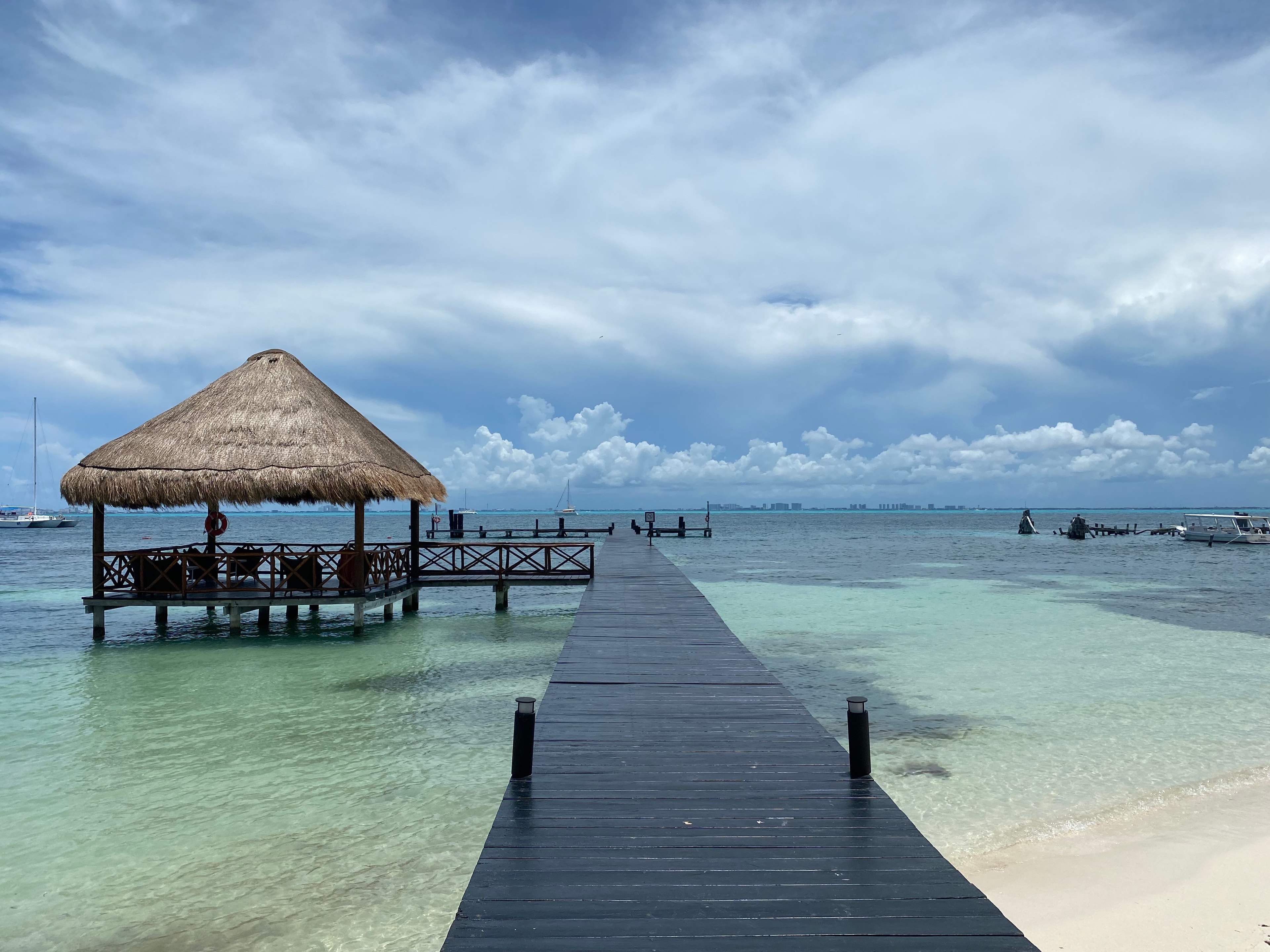 A beautiful view of a dock in the ocean with a hut for shade on a sunny day. 