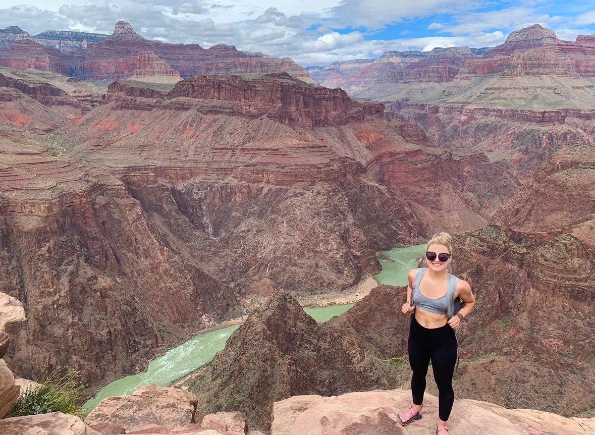 Advisor posing on a cliff with a valley below and a rushing river. 