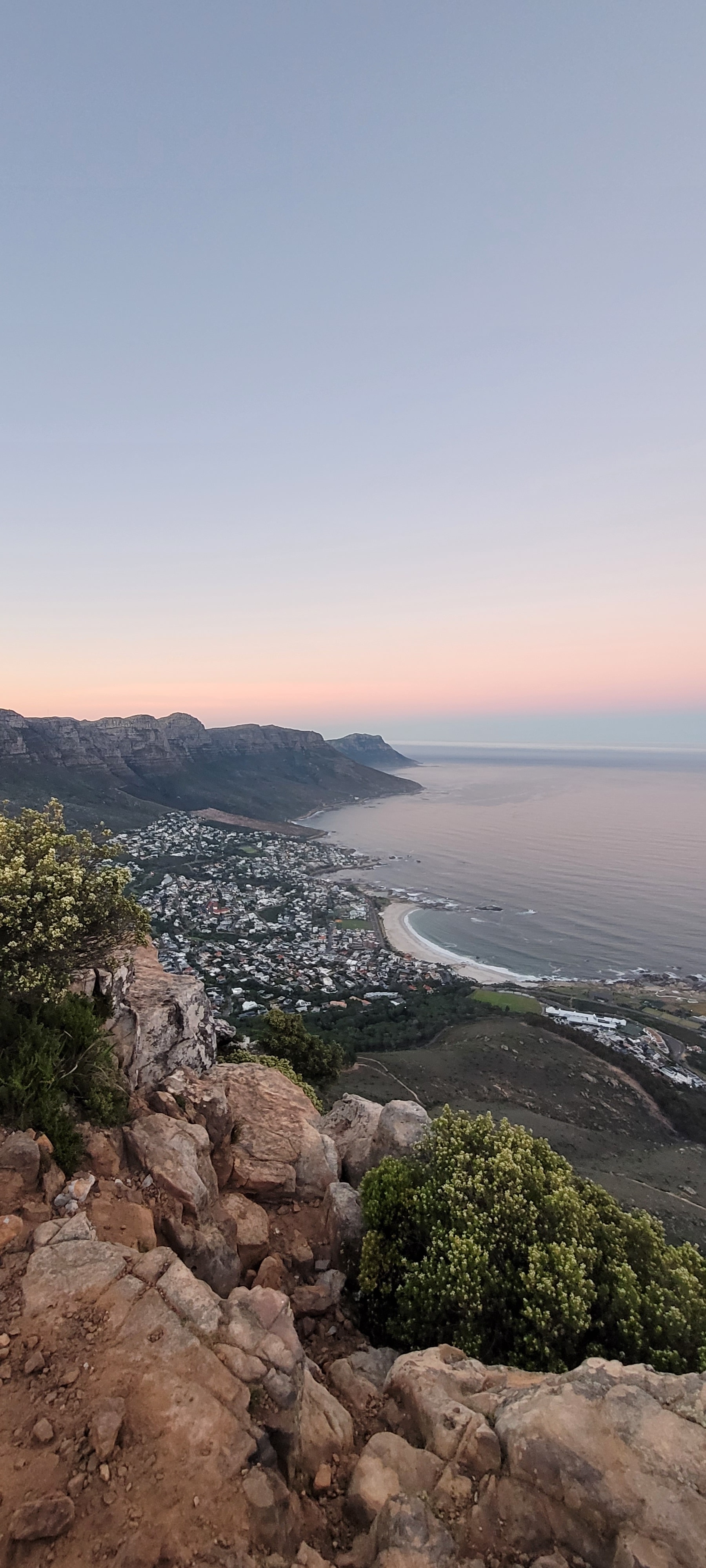 An aerial view of the ocean with rock formations and a beautiful sunset. 