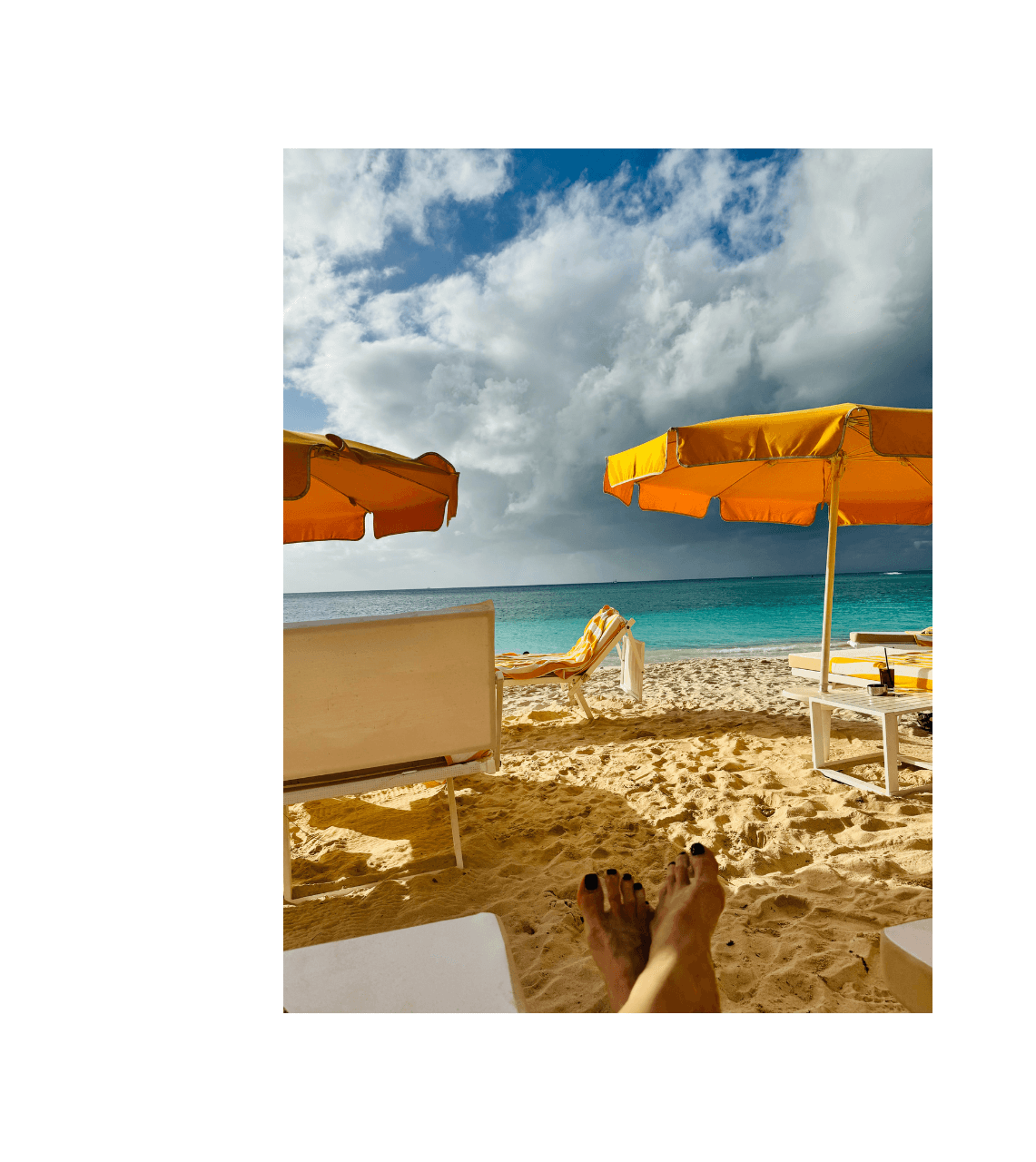 Advisor laying on the beach on a sunny day with an orange umbrella for shade on the beach.