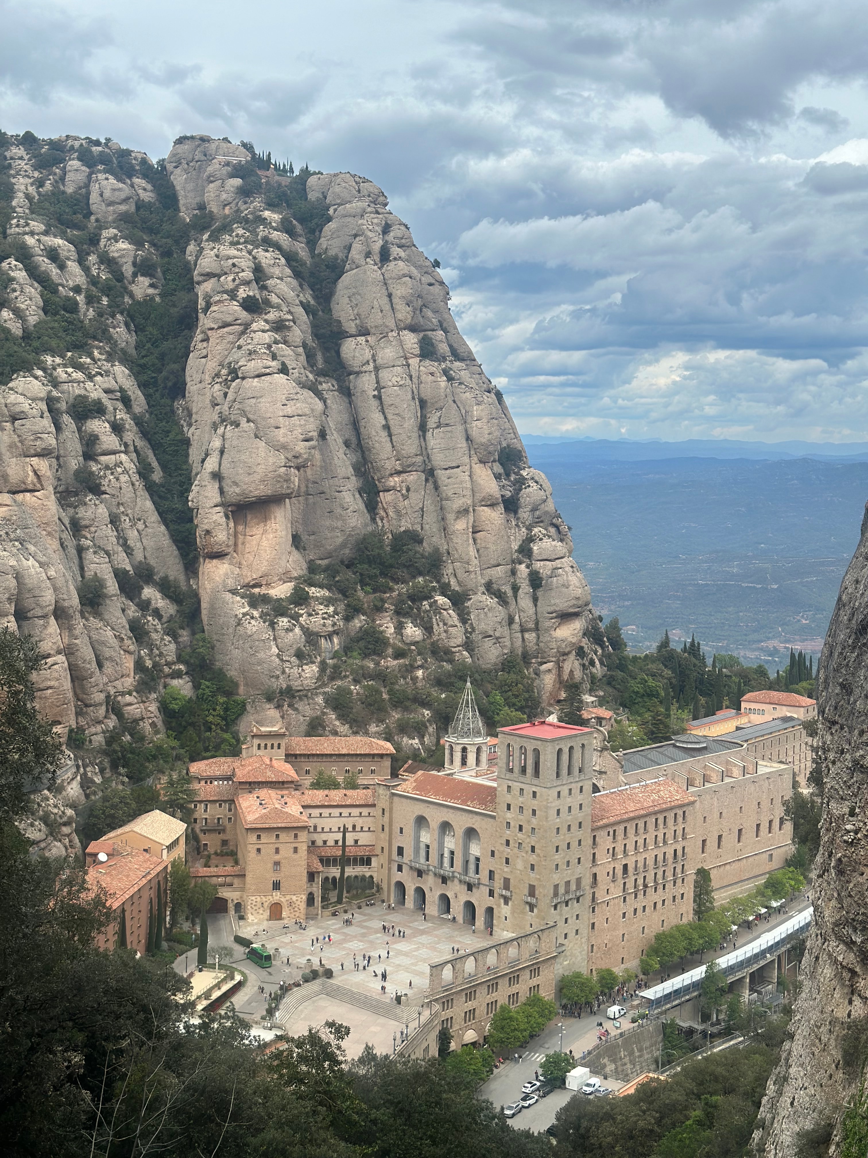 An image of town square at the bottom of a large cliff formation on a sunny day. 