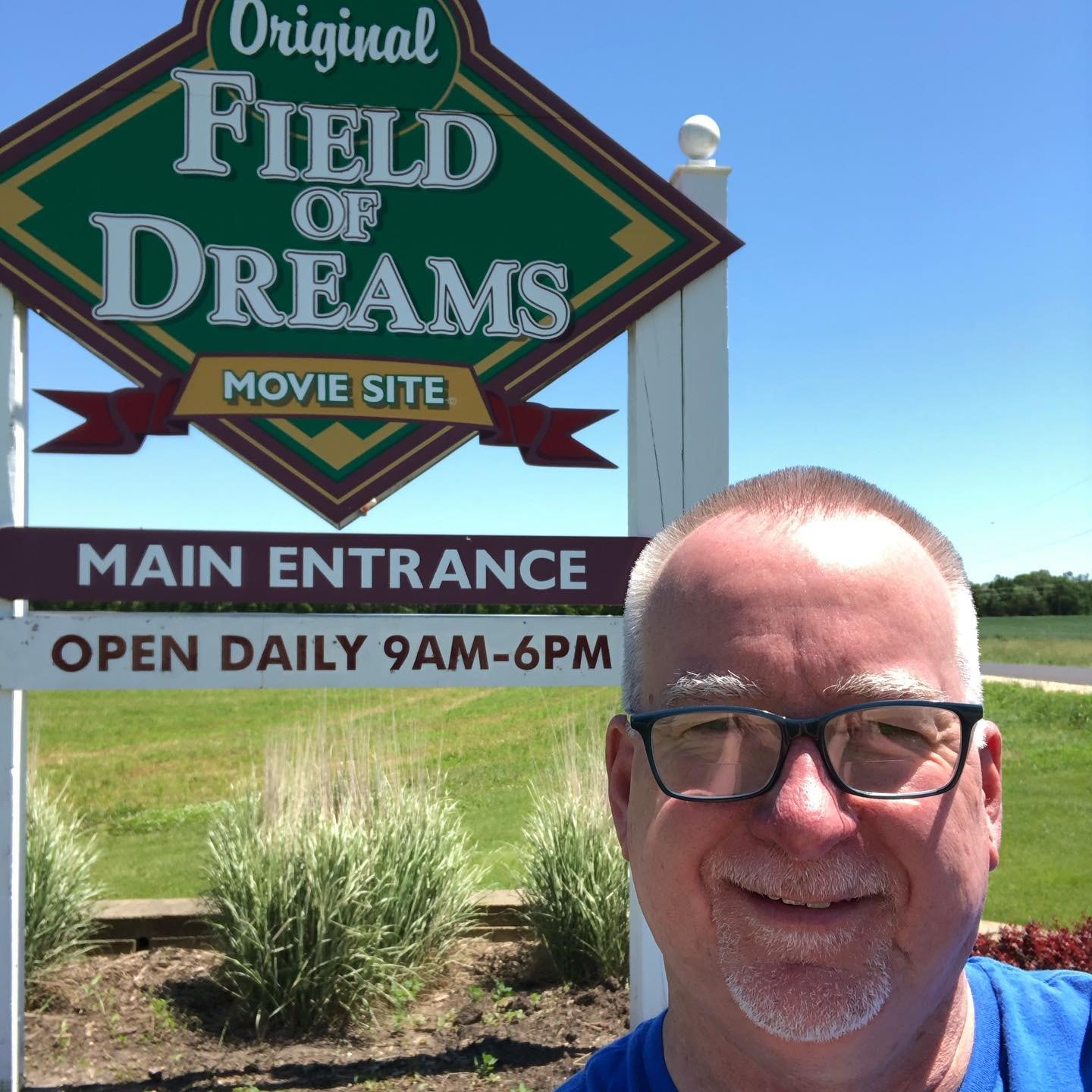 Advisor posing for an image in front of a 'Field of Dreams' sign on a sunny day. 