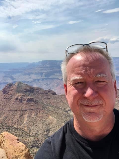 Advisor posing for an image with desert mountains in the distance on a sunny day. 