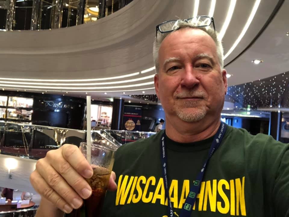 Advisor posing for an image with a Wisconsin shirt on and a beer in hand! 